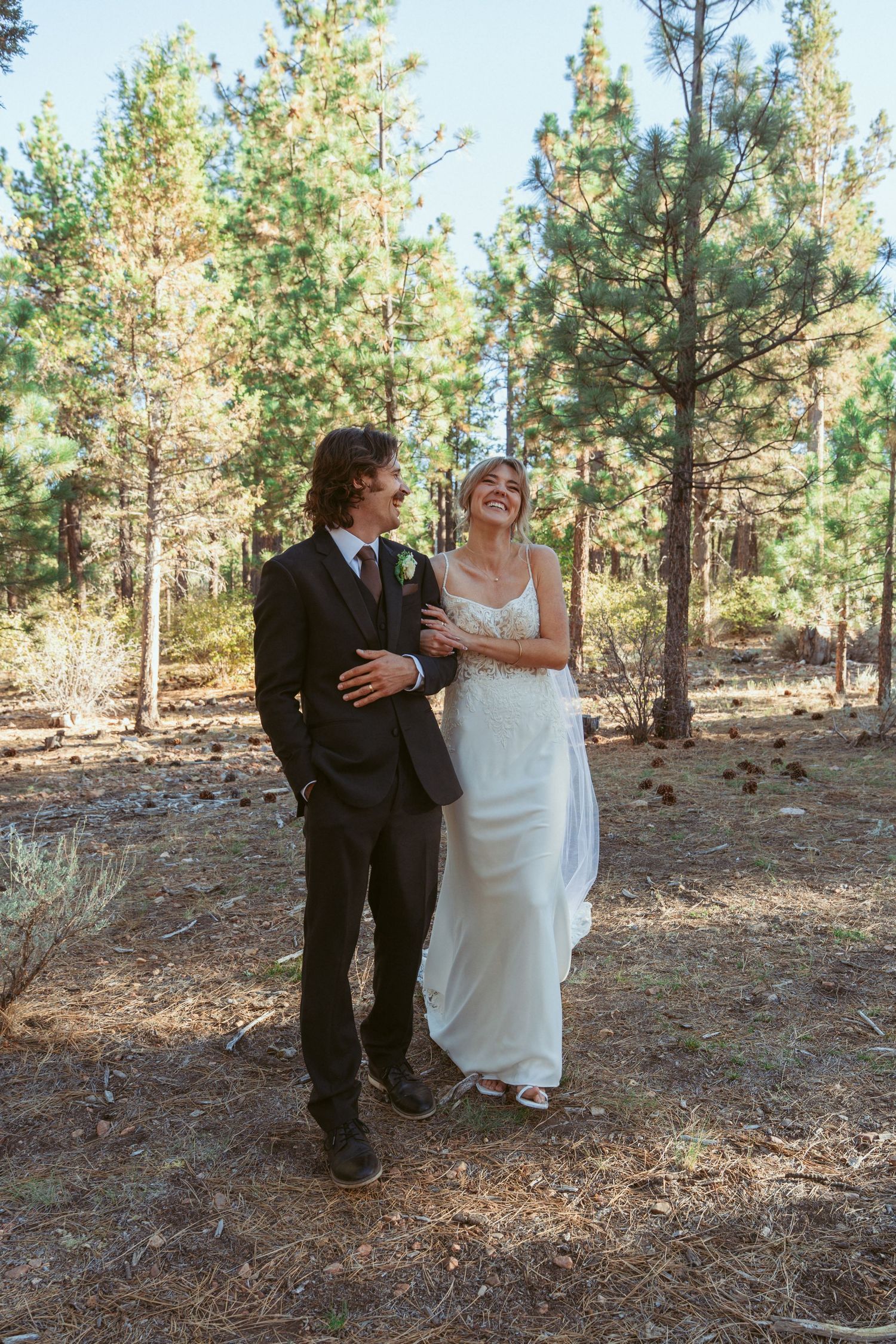 A romantic forest wedding photoshoot with pine trees creating a natural cathedral effect.