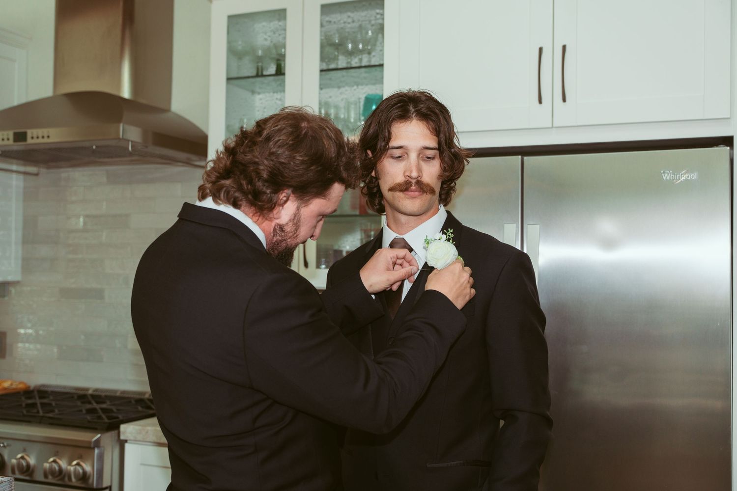 Wedding party members embracing in a modern kitchen setting.