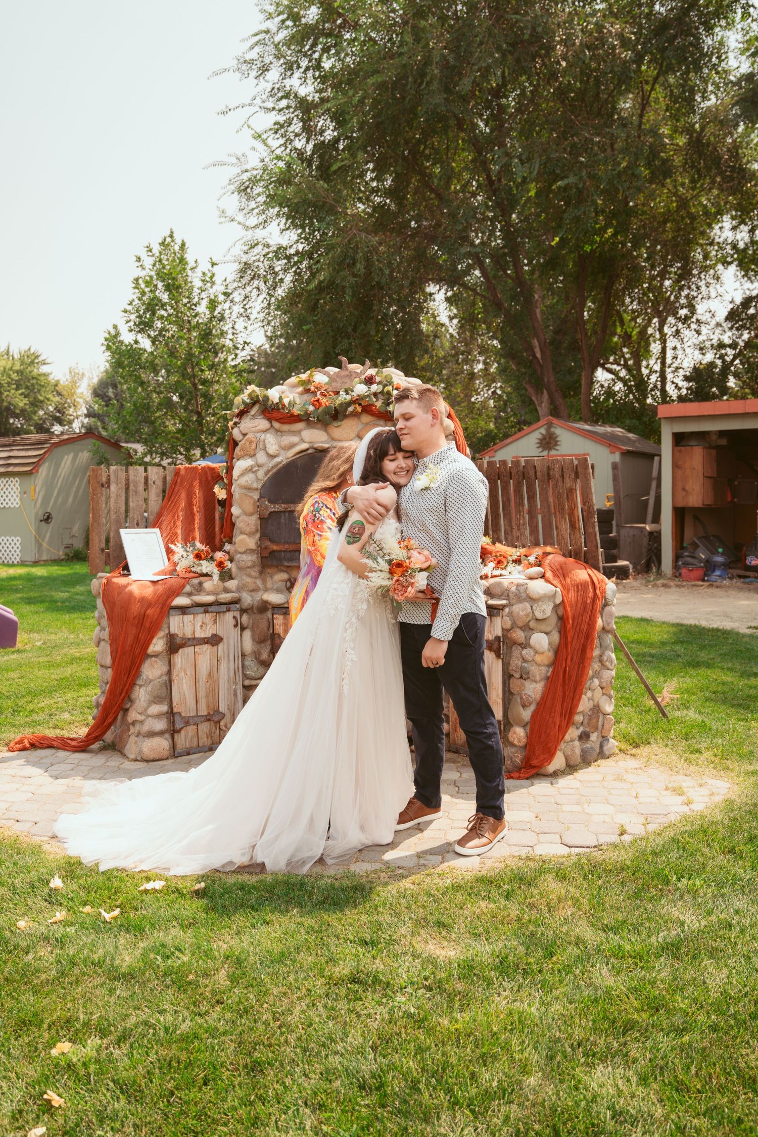 A couple shares a romantic dance moment in a garden setting with stone walls and orange draping.
