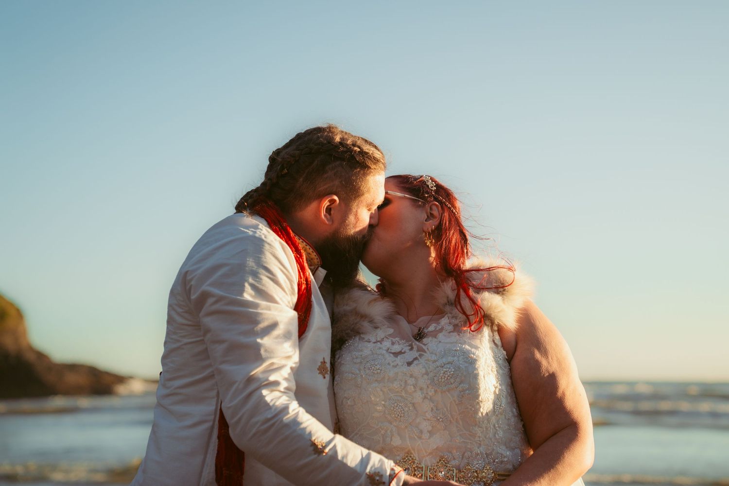 Tender moment between couple on beach with golden sunlight and ocean waves.