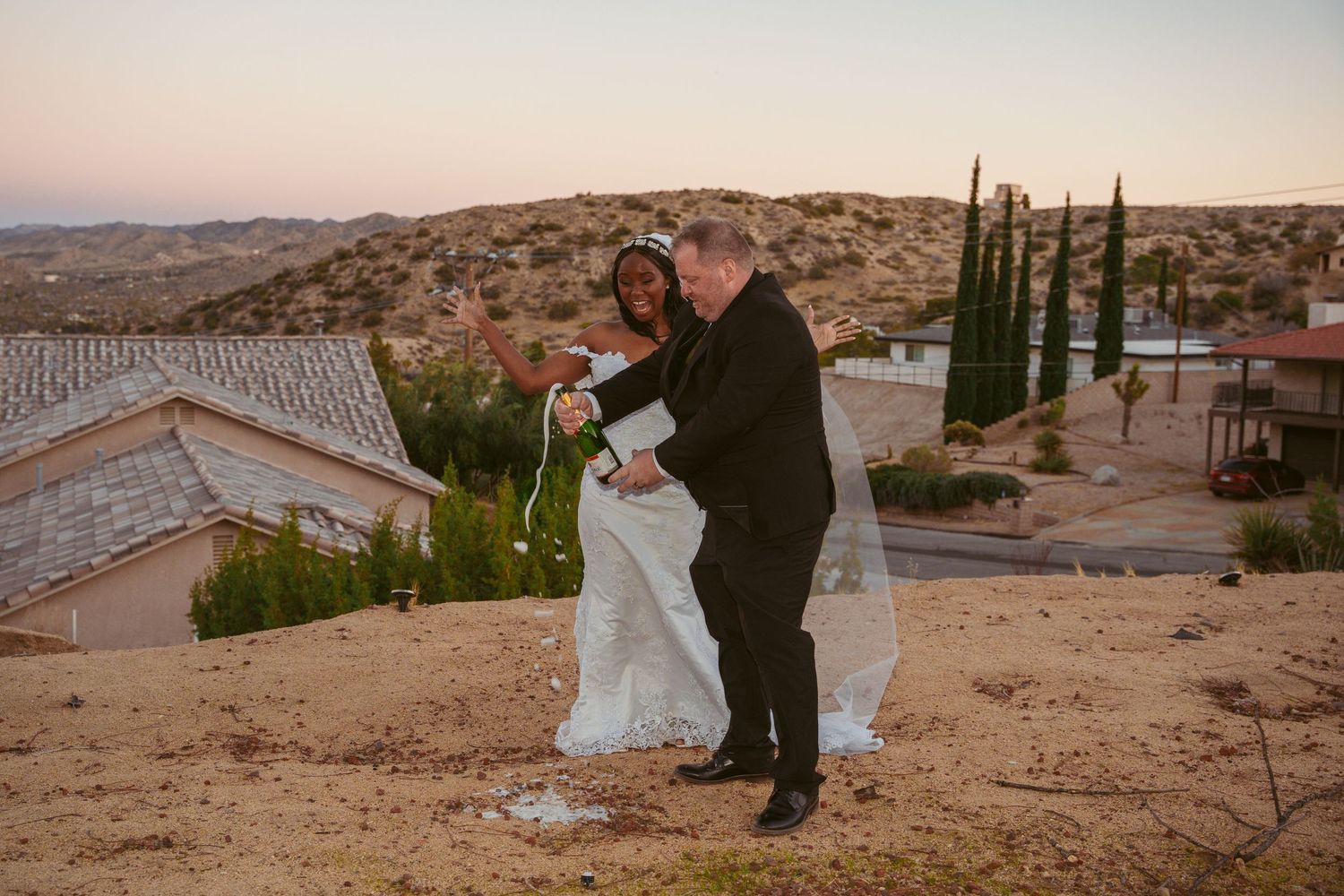 Desert landscape wedding photoshoot with desert mountains and cypress trees in background.