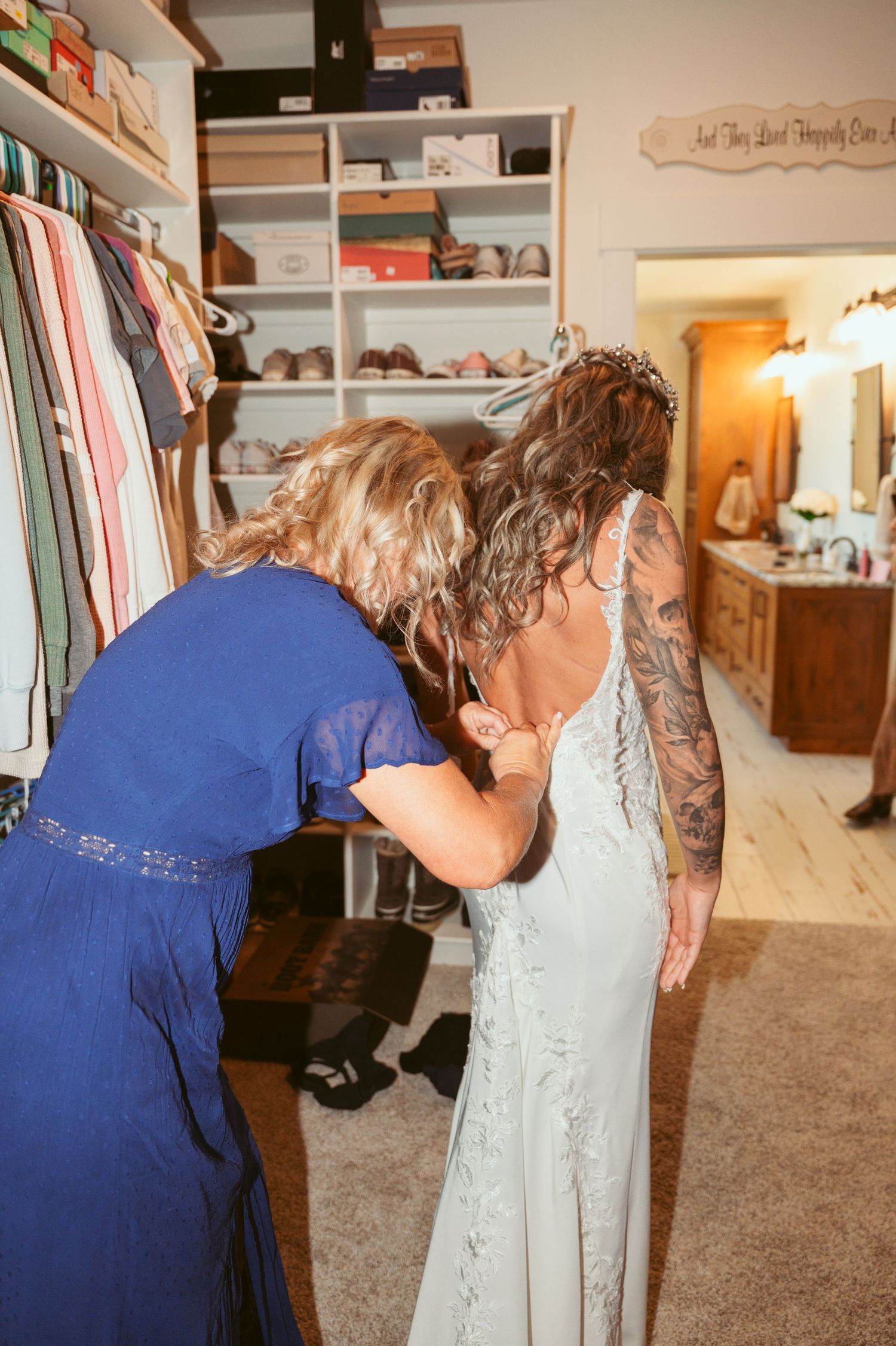 A walk-in closet with clothing racks and shelves where someone is trying on a light-colored dress.
