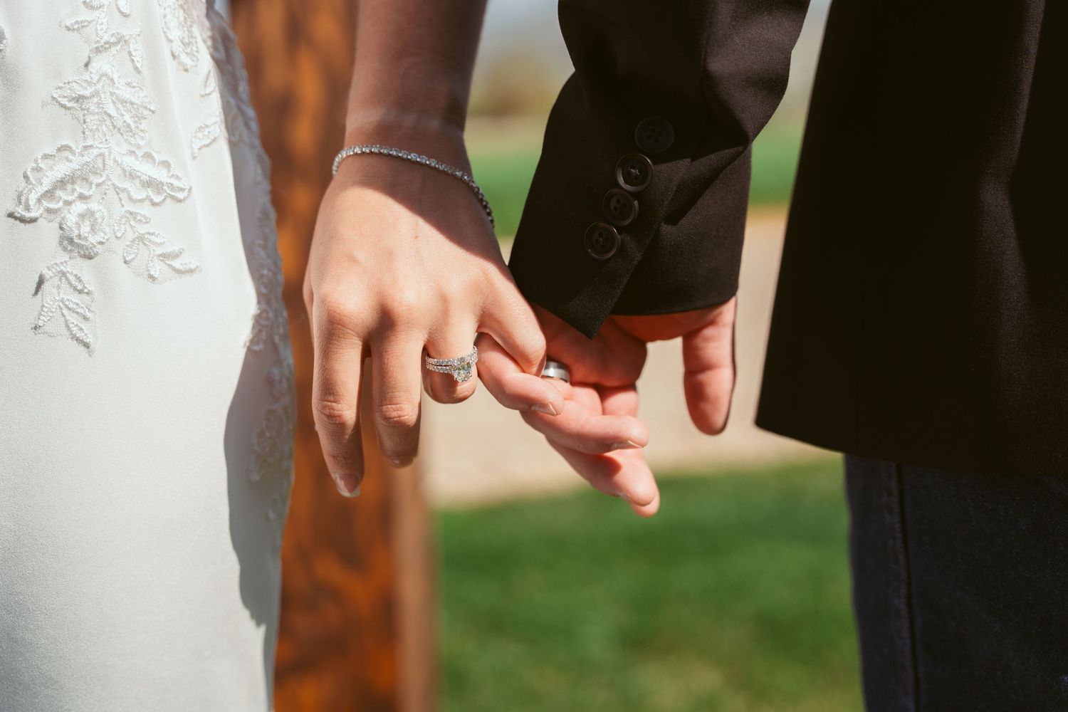 Close-up detail of hands and wedding dress lace during a ceremony.