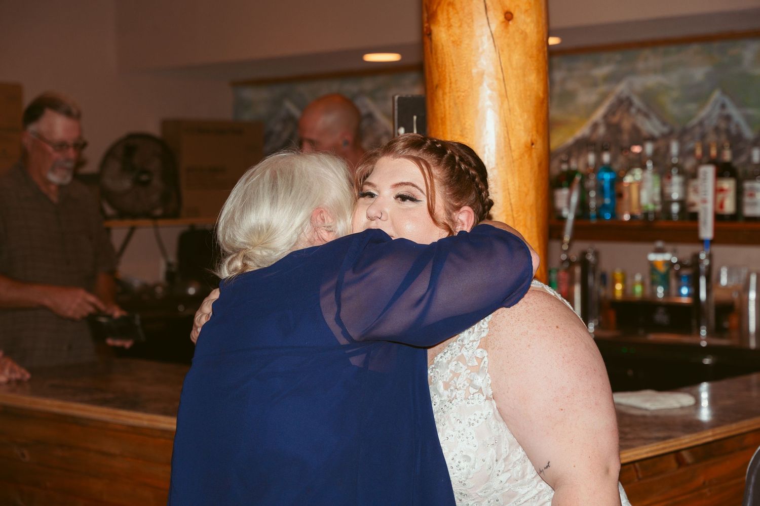 Wedding guests dance and celebrate at a rustic indoor reception venue with wooden decor.