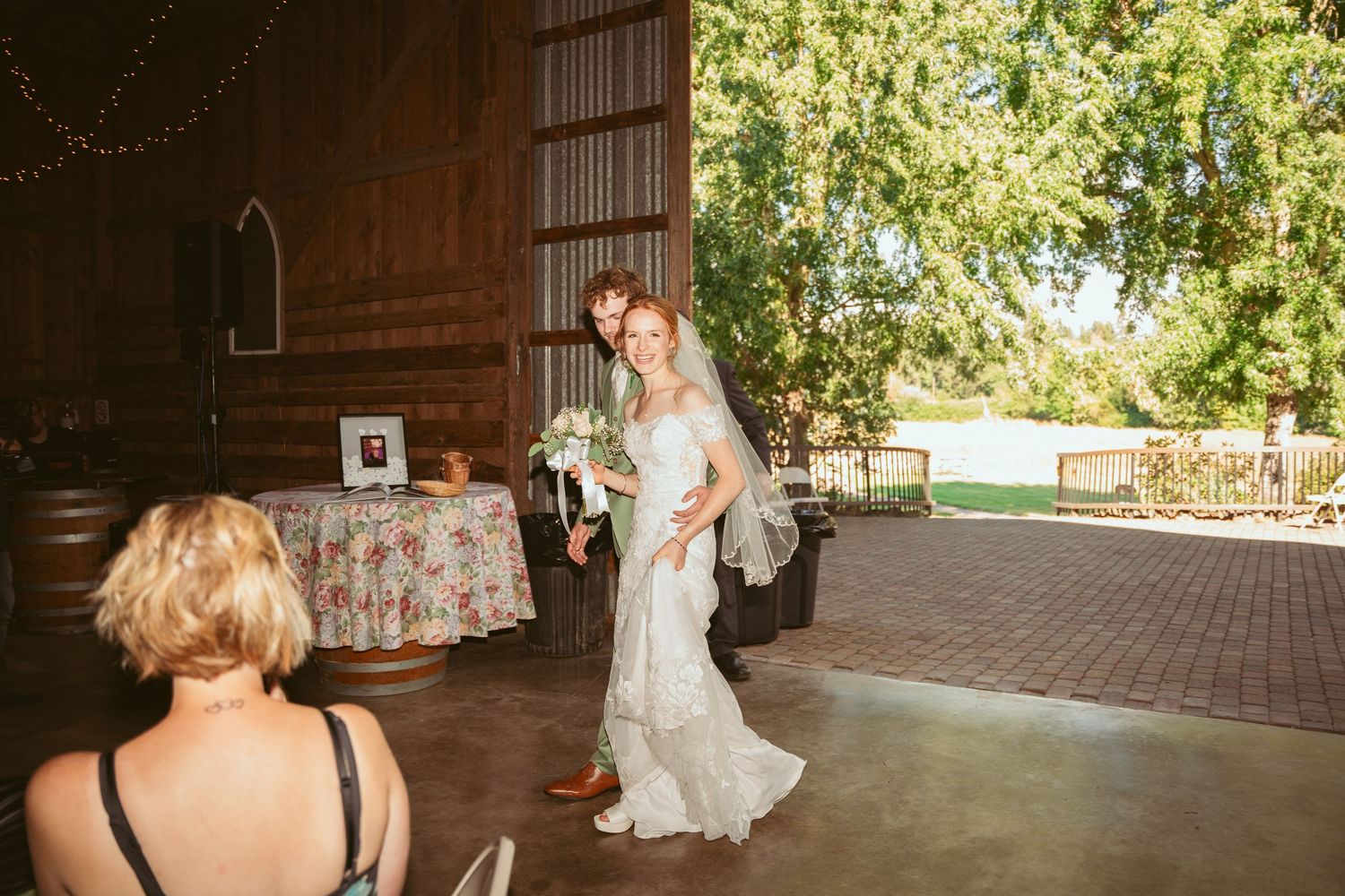 Spacious barn venue with natural lighting streaming through large doorways.