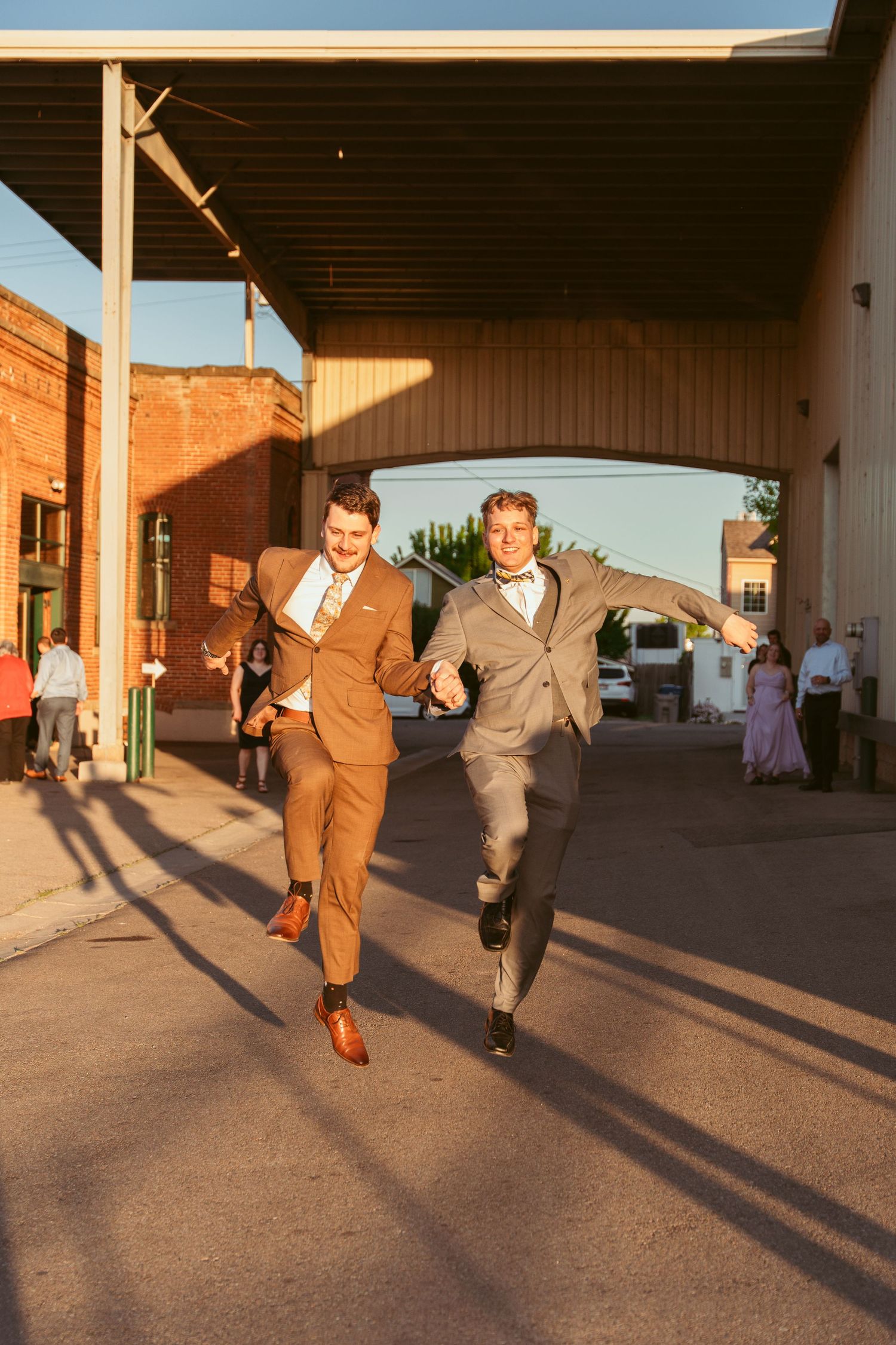Men in suits sprinting across a concrete patio during golden hour creating dramatic shadows.