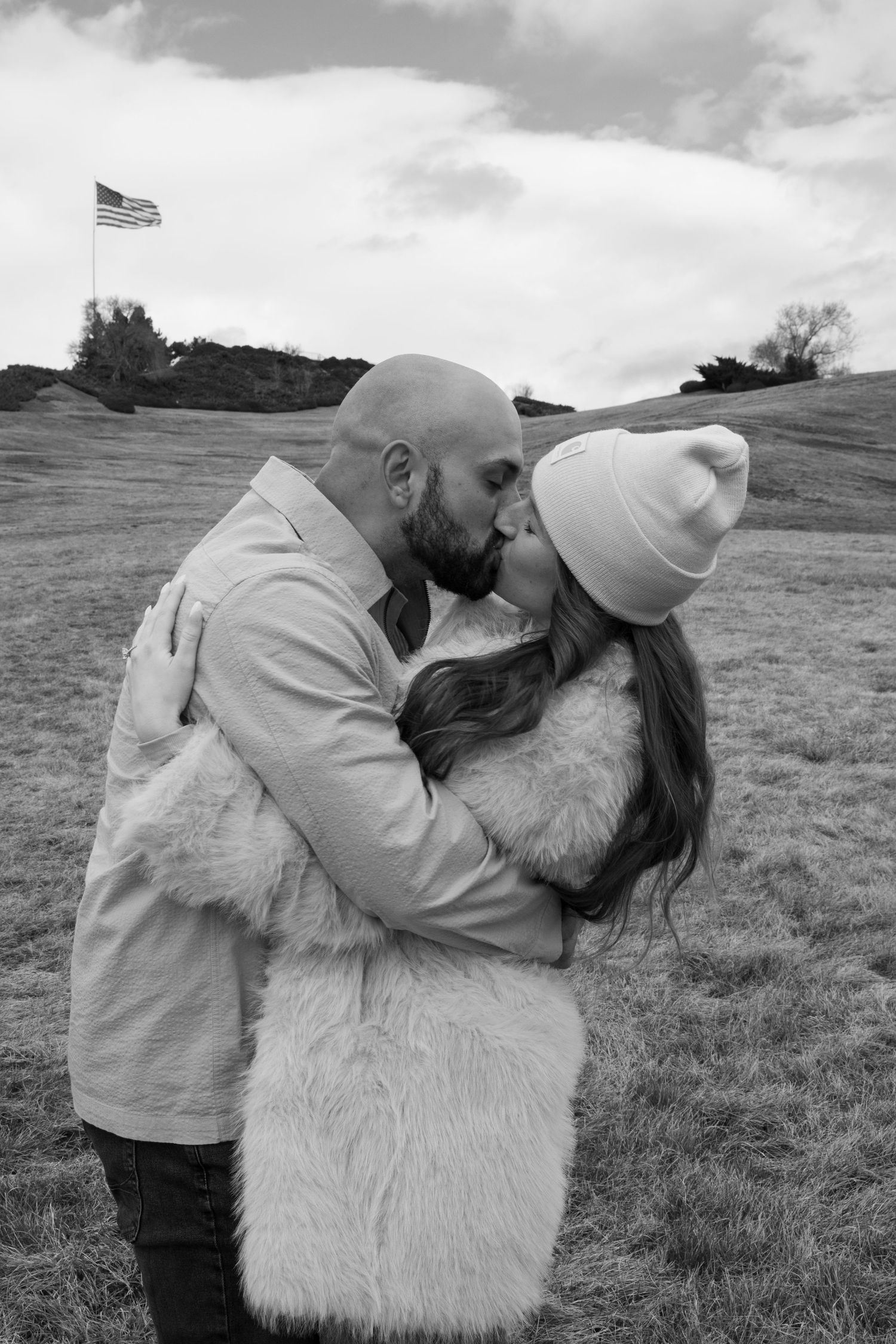 Black and white photos show a person embracing a large fluffy white dog in a grassy field with an American flag visible.