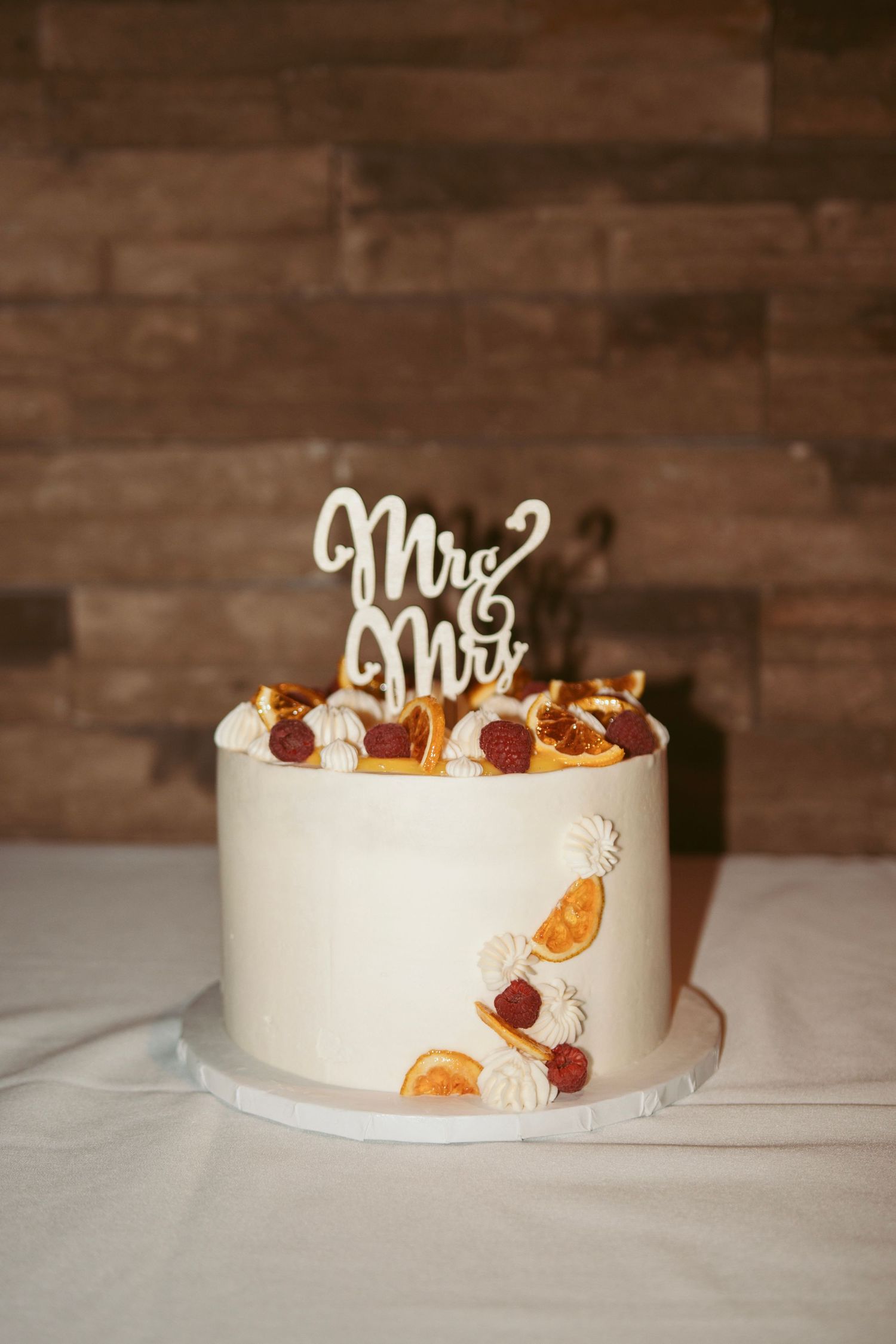 Elegant white wedding cake decorated with dried orange slices and floral accents.