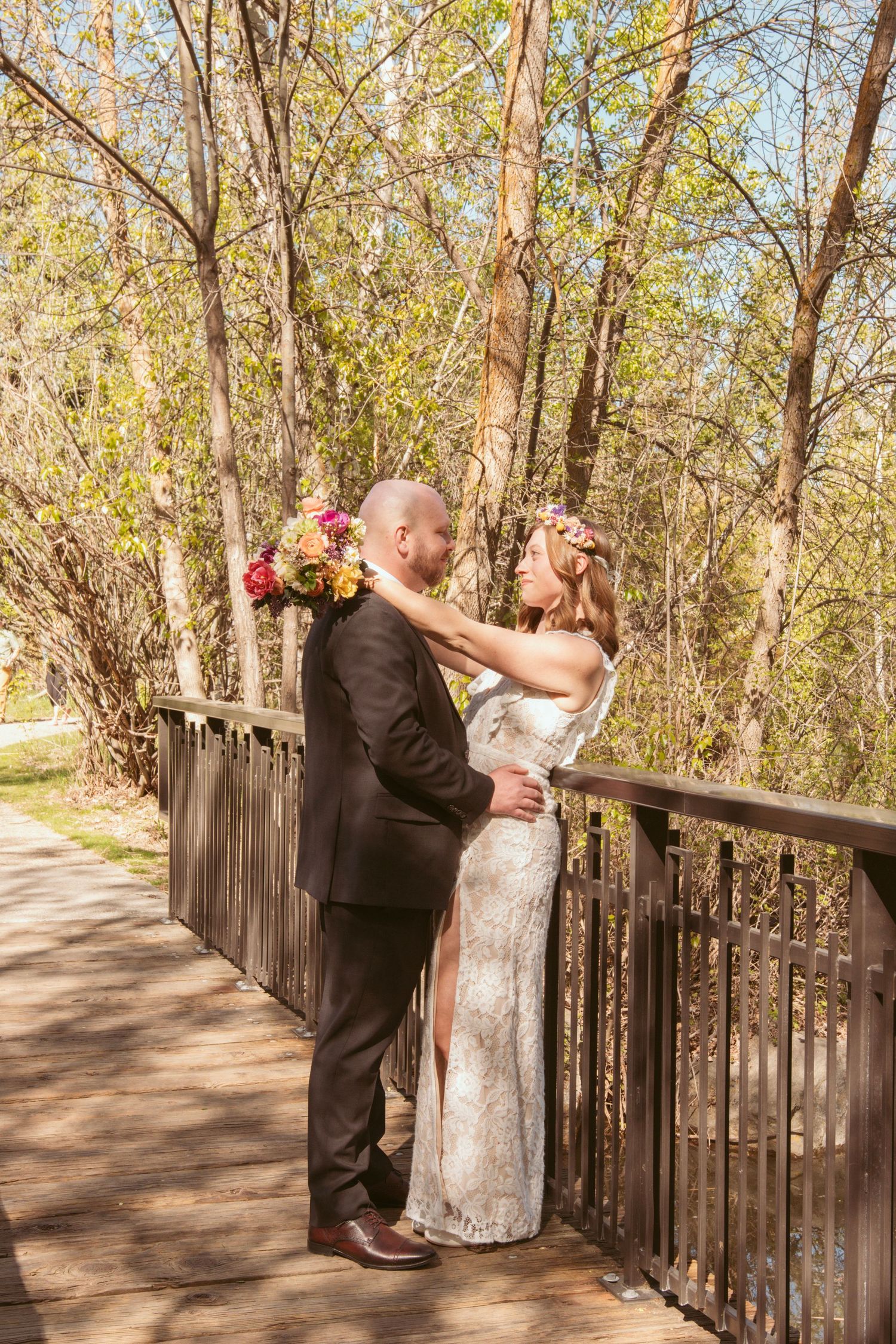 A tender moment between newlyweds on a rustic wooden bridge in autumn.