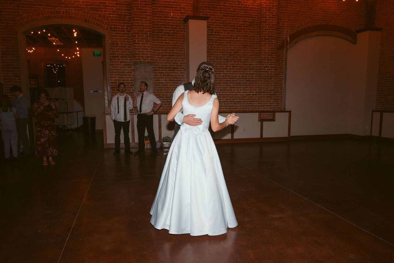 Wedding reception dance in a vintage brick venue with warm lighting and guests.