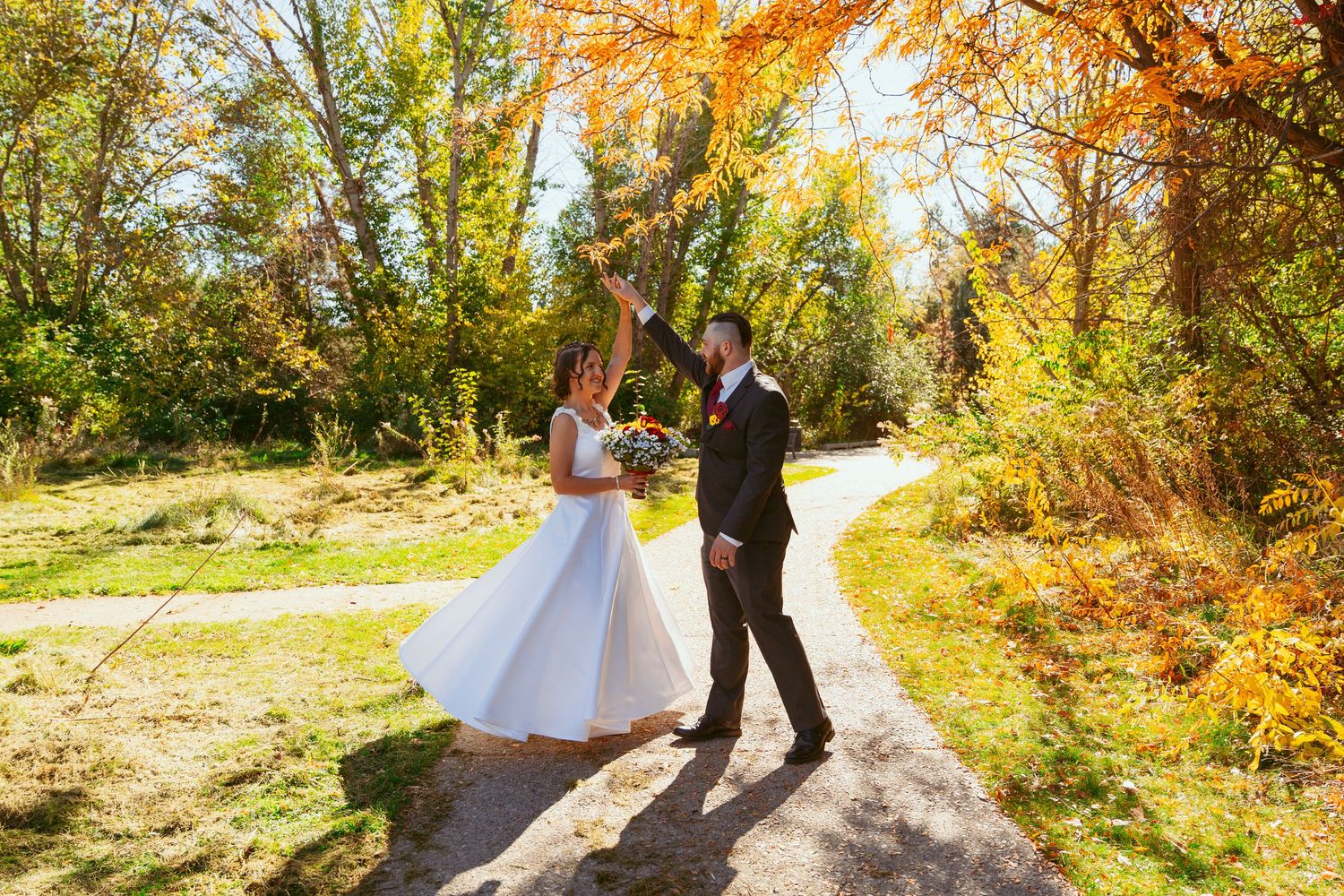 Newlyweds share an intimate dance moment surrounded by fall foliage.