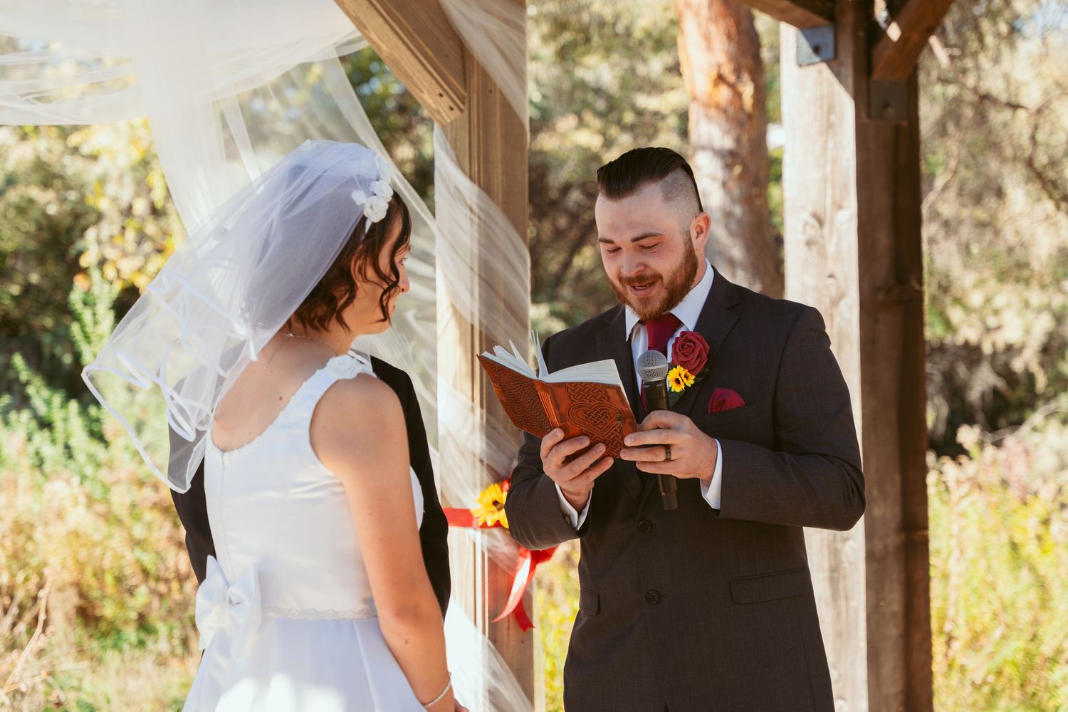 Emotional wedding ceremony moment captured under a rustic wooden pavilion with autumn decor.
