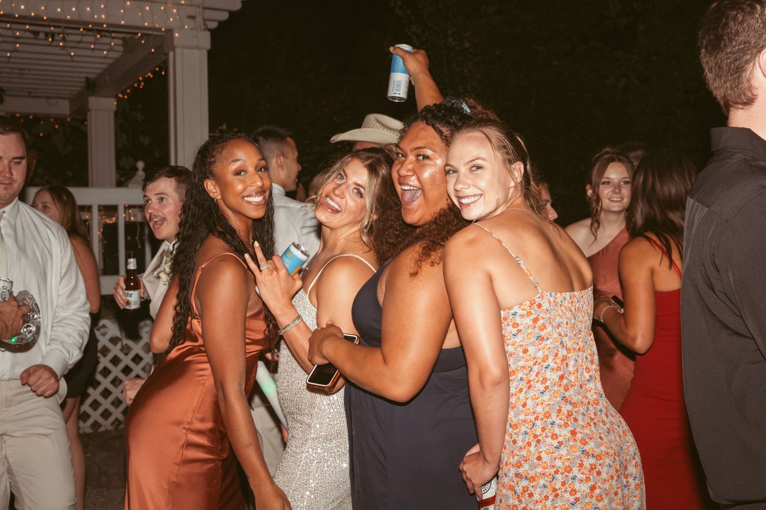 Wedding guests in formal attire dancing and celebrating at an outdoor reception.