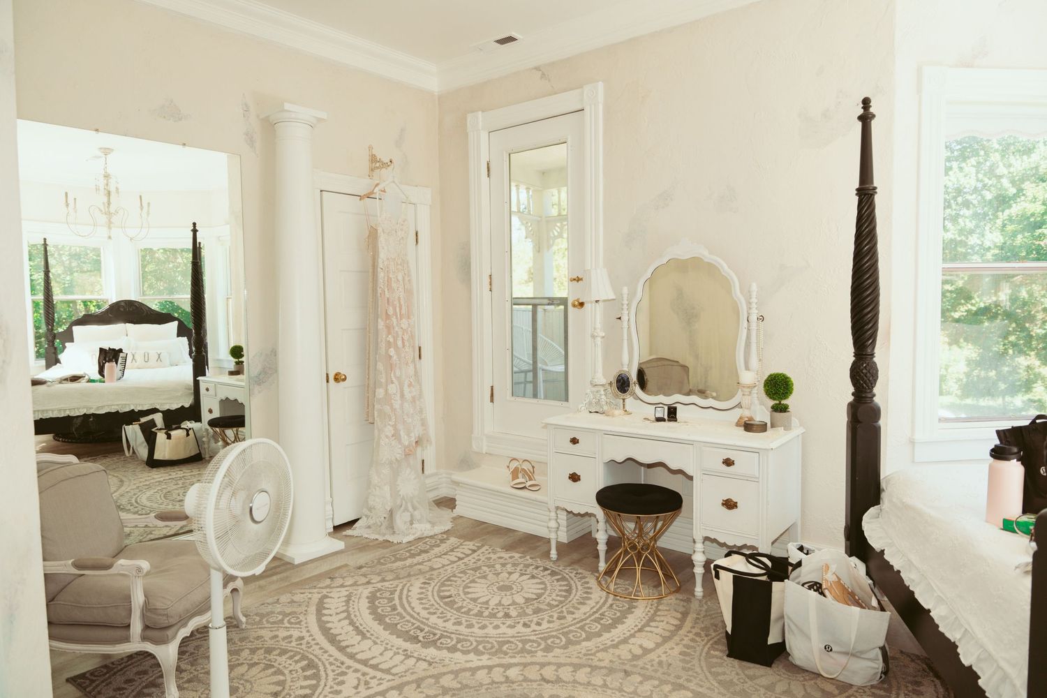 Elegant all-white bedroom interior with four-poster bed, curved walls, and large windows letting in natural light.