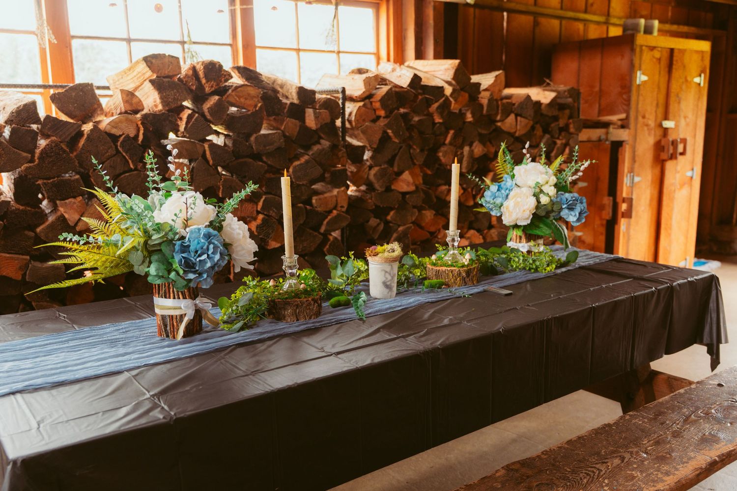 Elegant table decor with blue floral arrangements and candles against a dark backdrop.