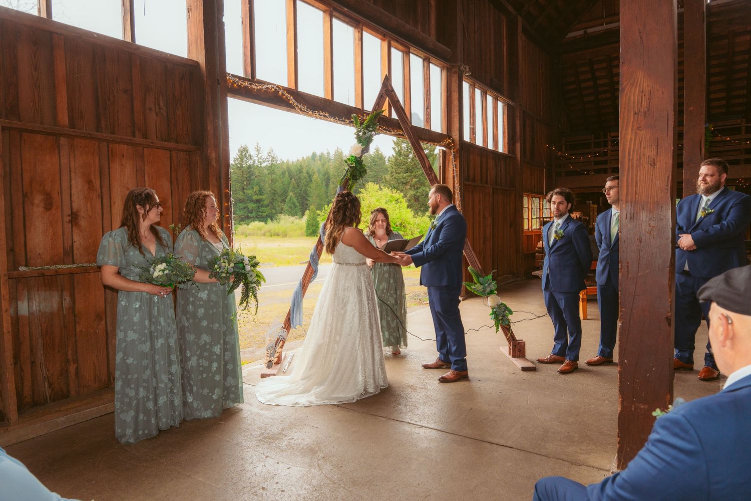Sunlit barn wedding venue with wooden beams and large windows creating natural lighting.