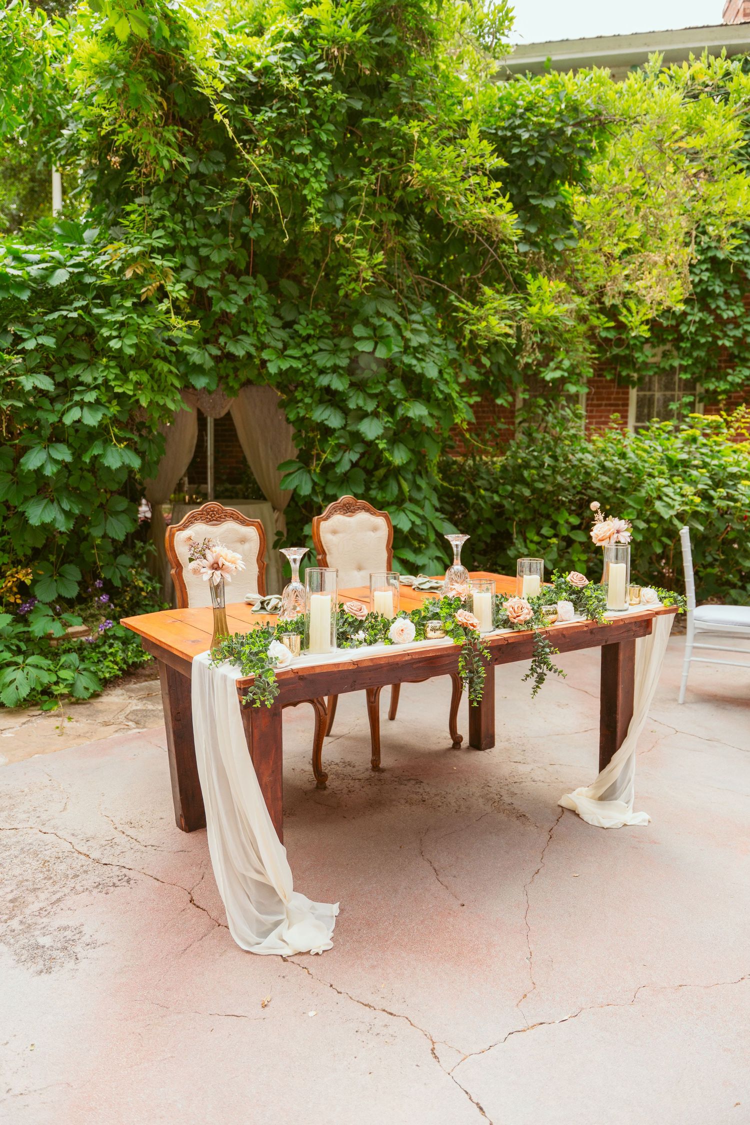 Elegant vintage chairs and tables set up in a garden setting for a wedding reception.