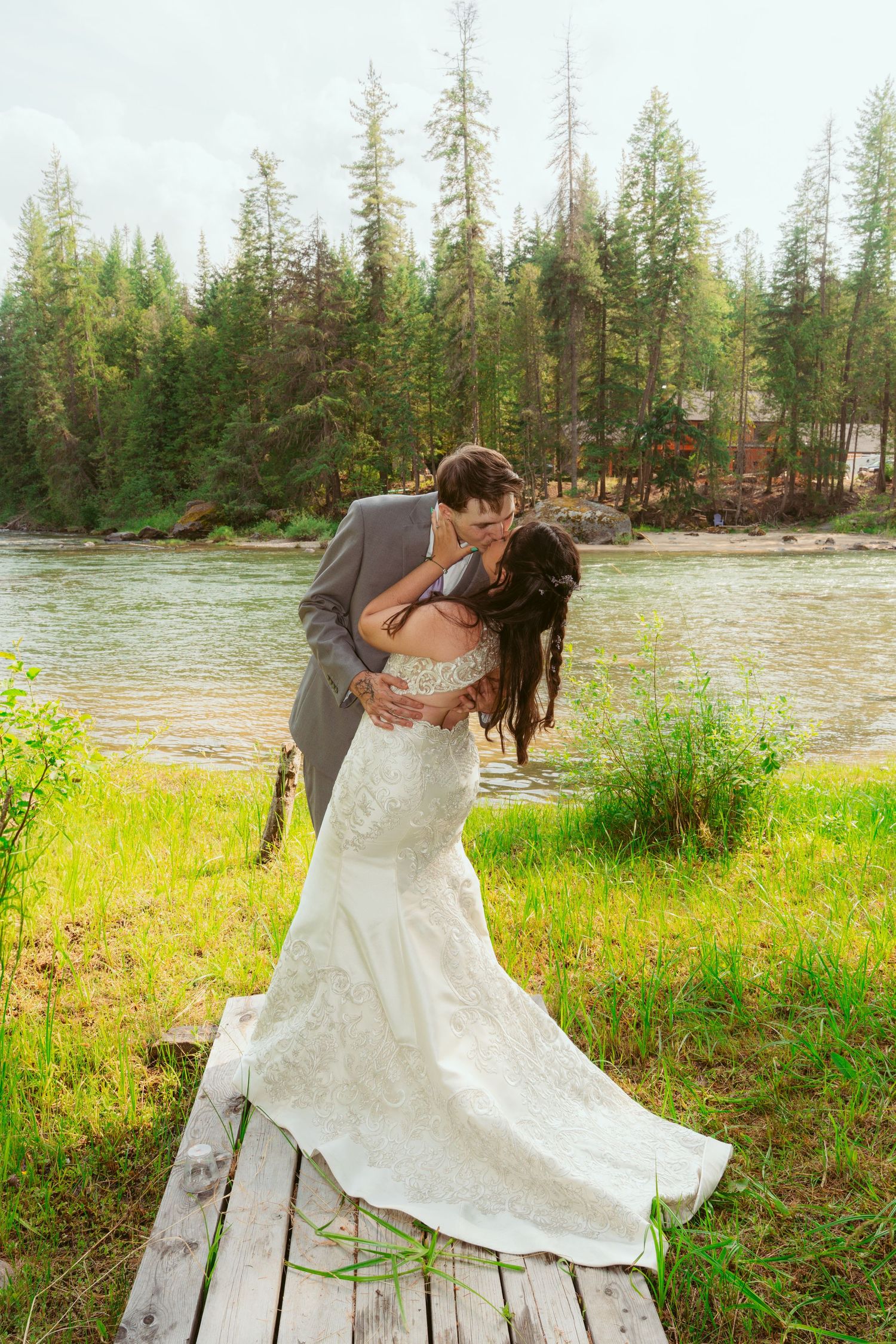A couple dancing and twirling in a scenic meadow with evergreen trees in the background.