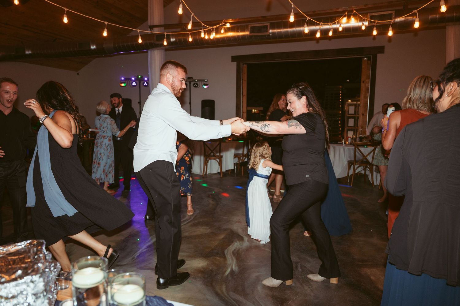 People dancing and socializing at an indoor wedding reception with warm lighting.