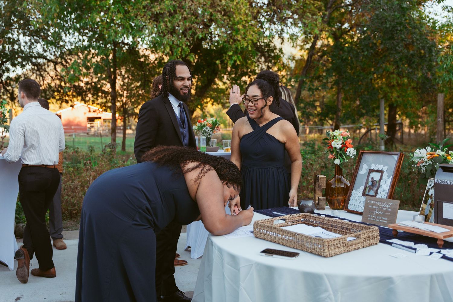 Outdoor wedding reception dessert table with treats and decorations at sunset.