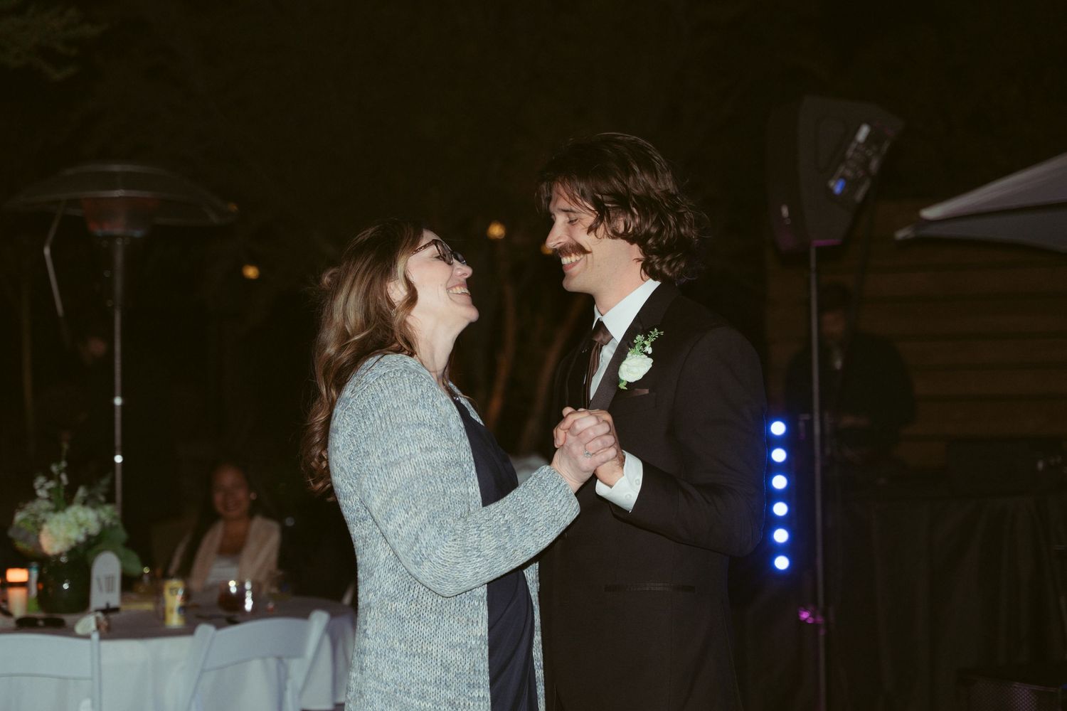 Couple dancing together at night with blue stage lights illuminating their formal attire.