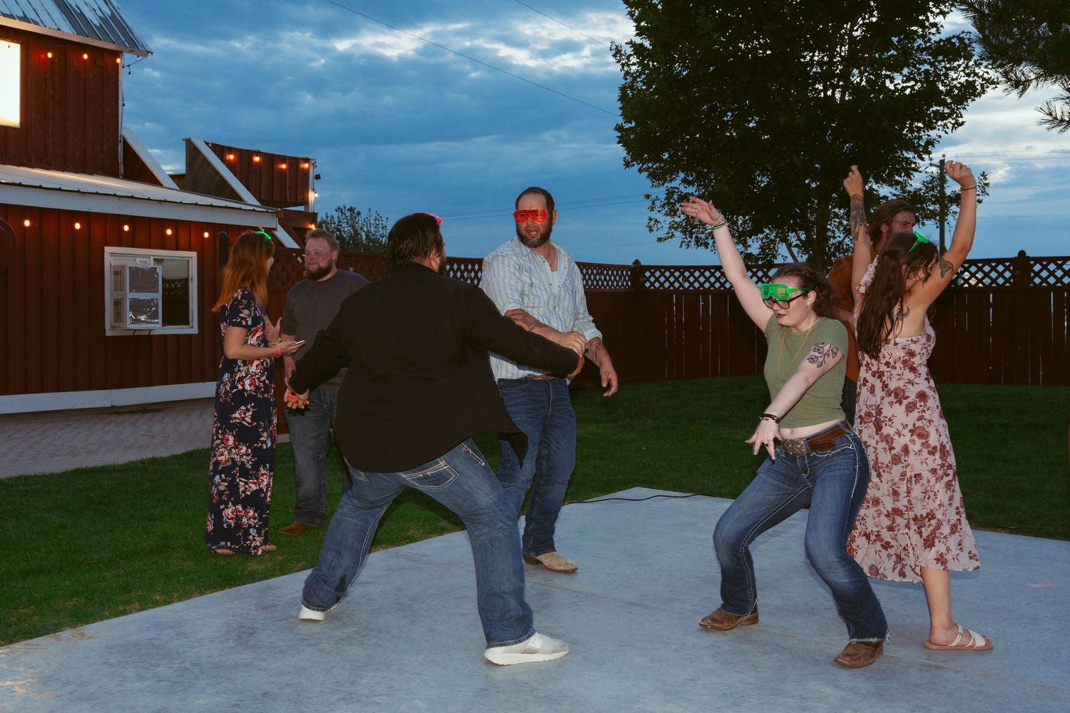 Wedding guests dancing and celebrating on an outdoor patio at dusk.