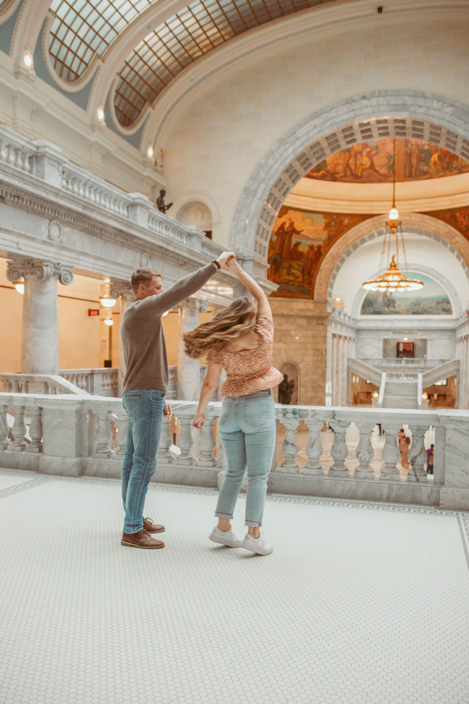 Dancing together in an elegant marble hallway with classical architecture.
