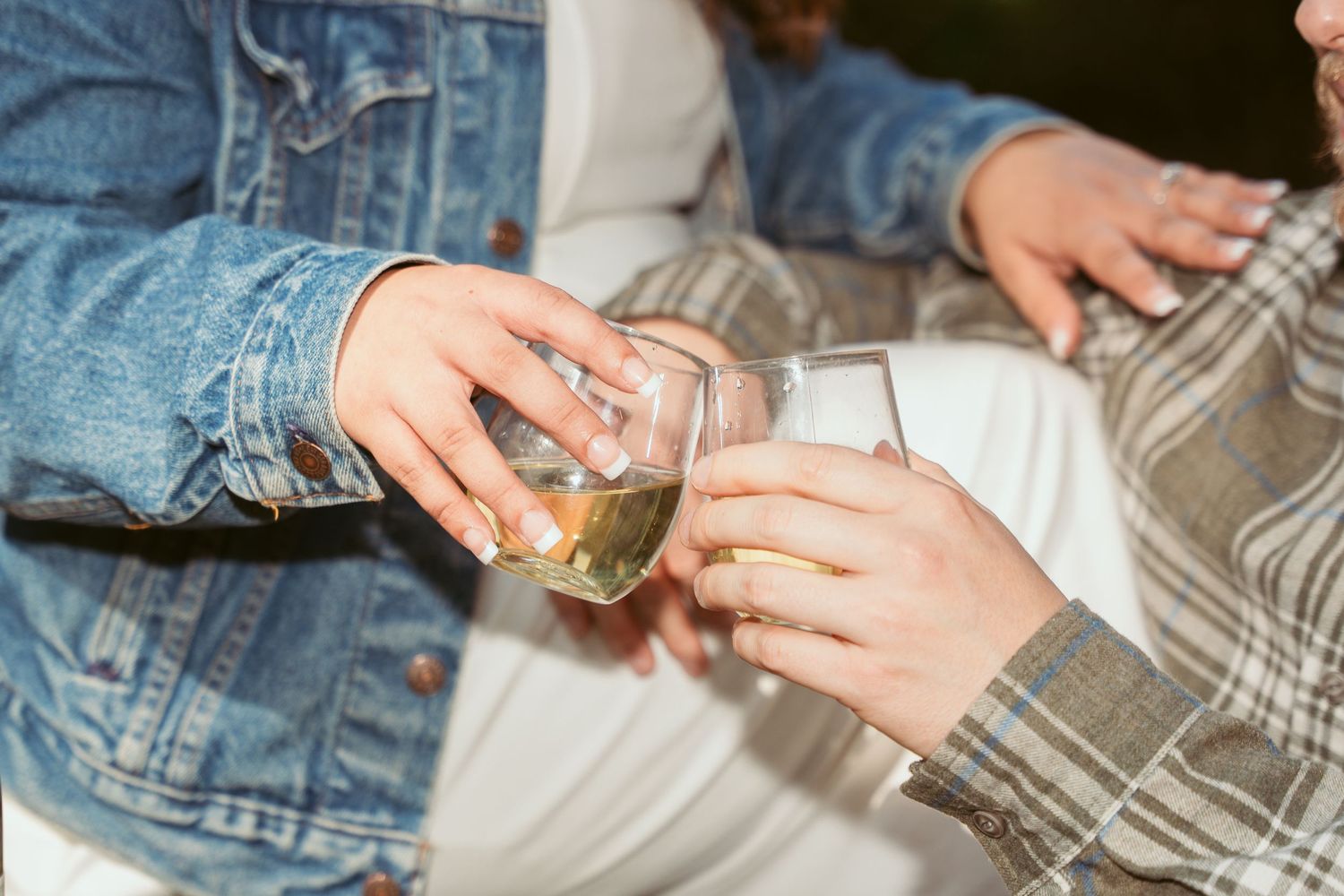 Close-up of hands holding champagne glasses during outdoor celebration.