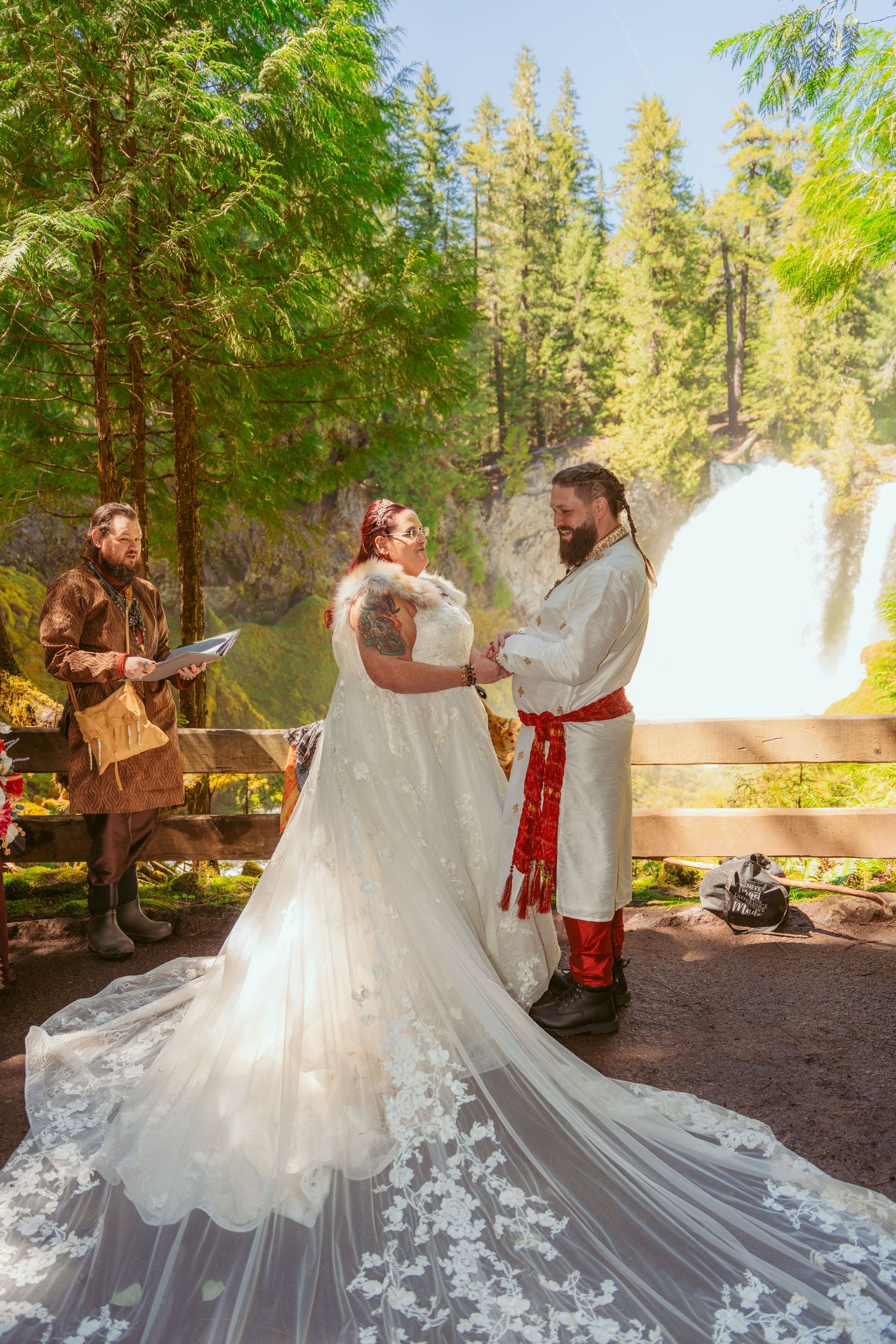 Scenic forest wedding with flowing white dress train and evergreen surroundings.