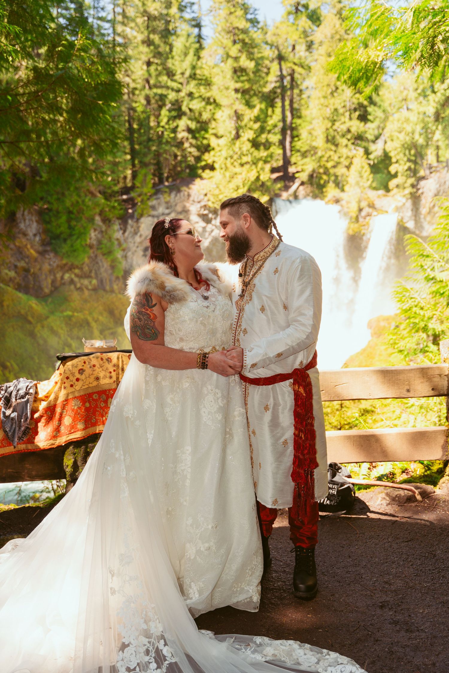 A couple shares a joyful moment during their forest wedding with a waterfall in the background.