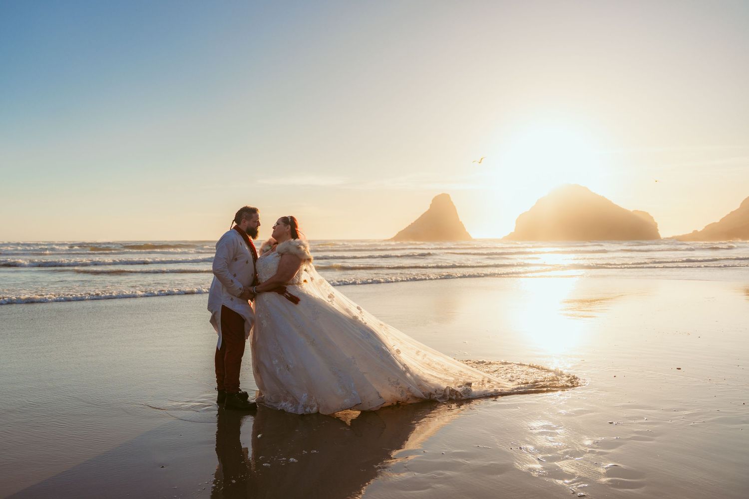A romantic beach wedding photoshoot with dramatic sunset and ocean waves.
