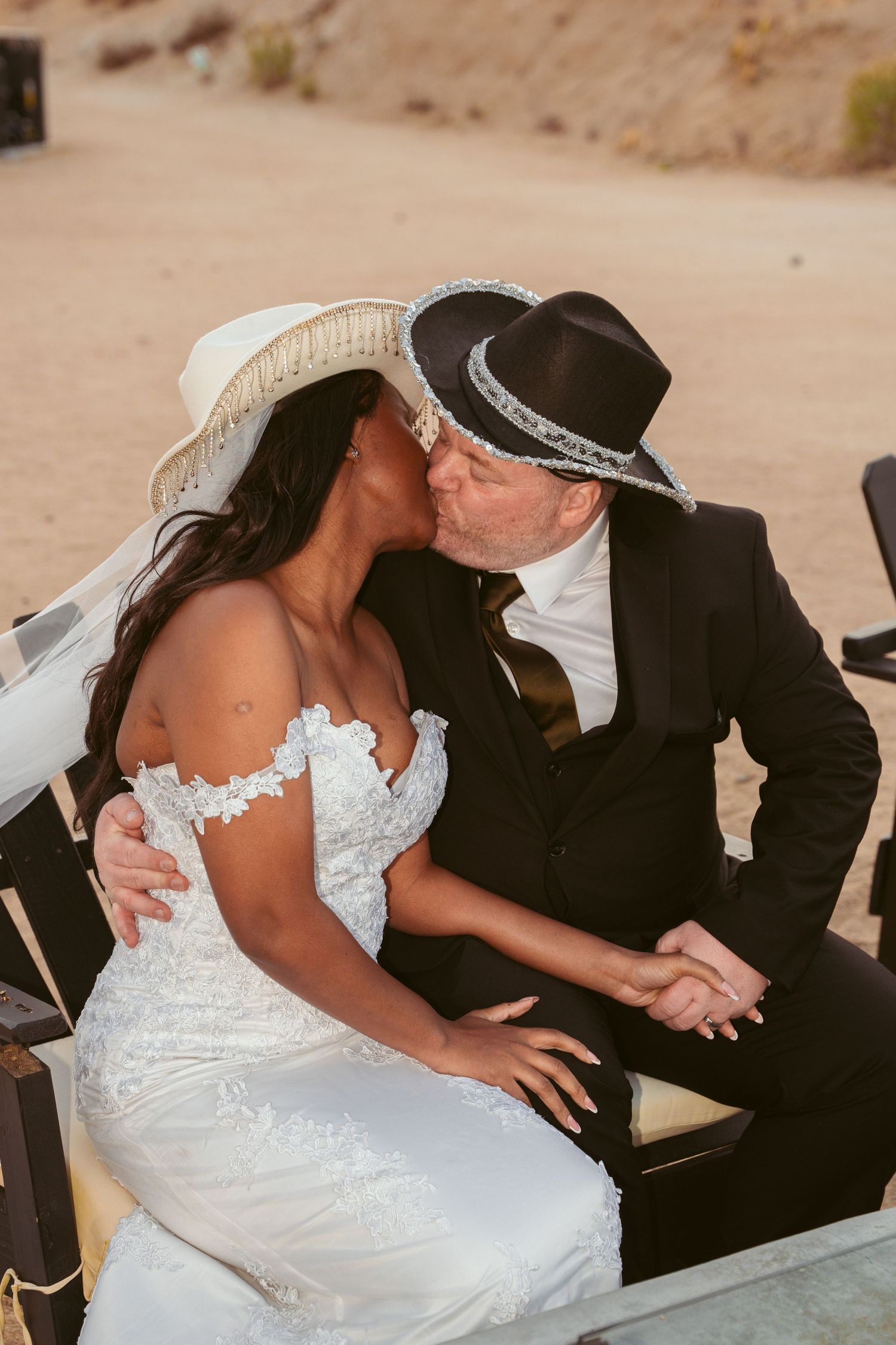 Newlyweds share tender moments while seated in Adirondack chairs outdoors.