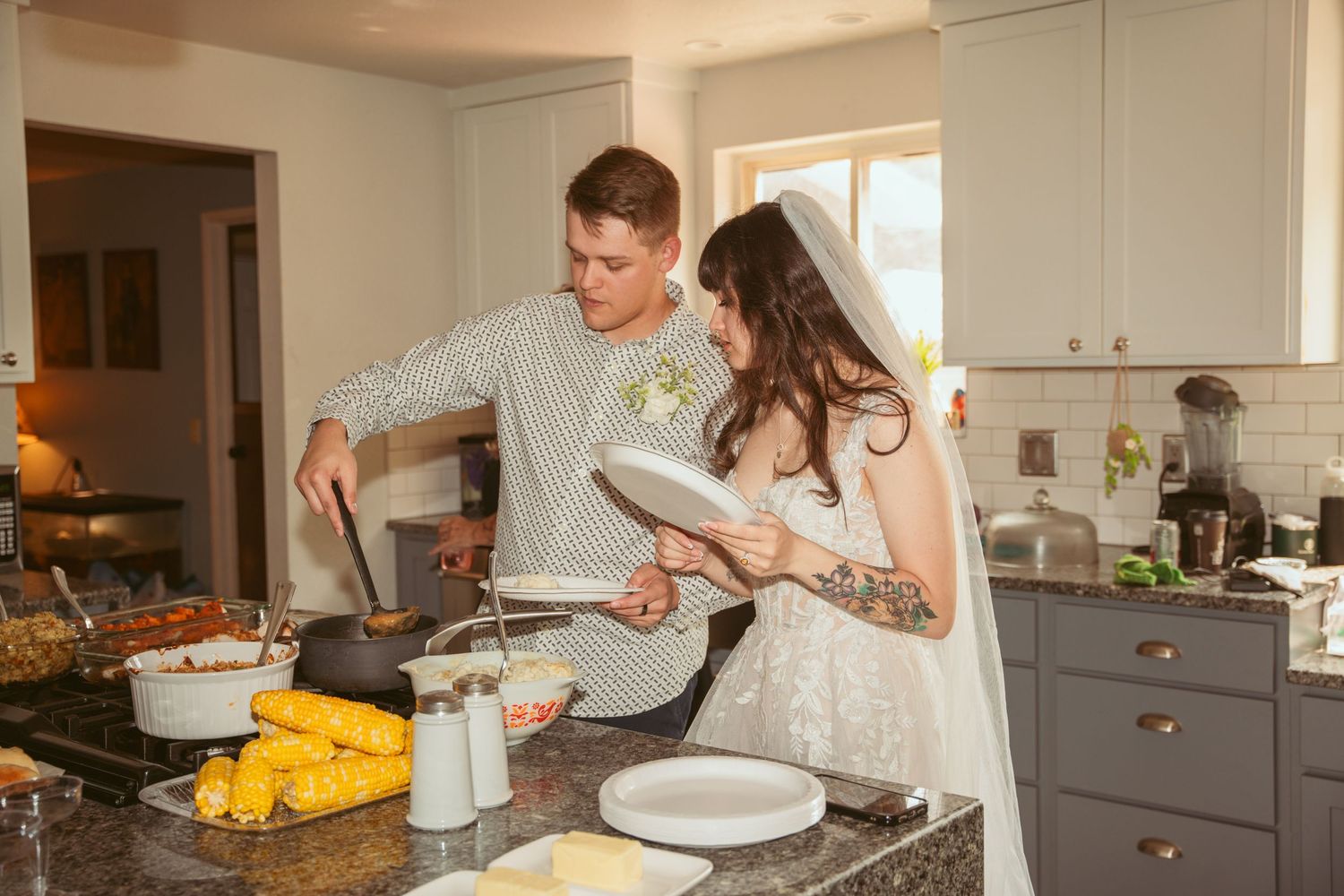 Couple cooking together in a modern kitchen with white cabinets and countertops.