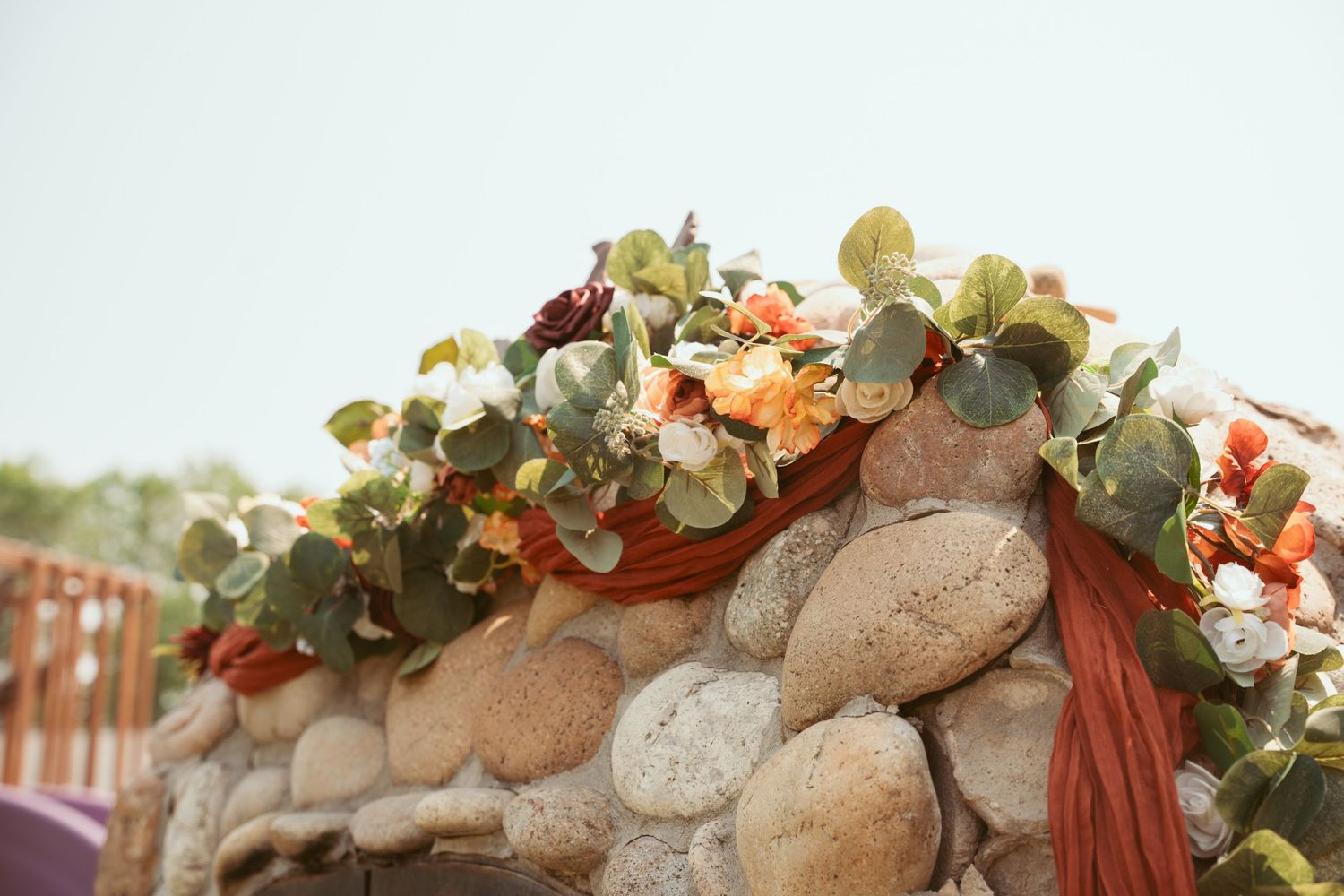 Decorative stone wall adorned with peach and cream floral arrangements and rust-colored fabric accents.