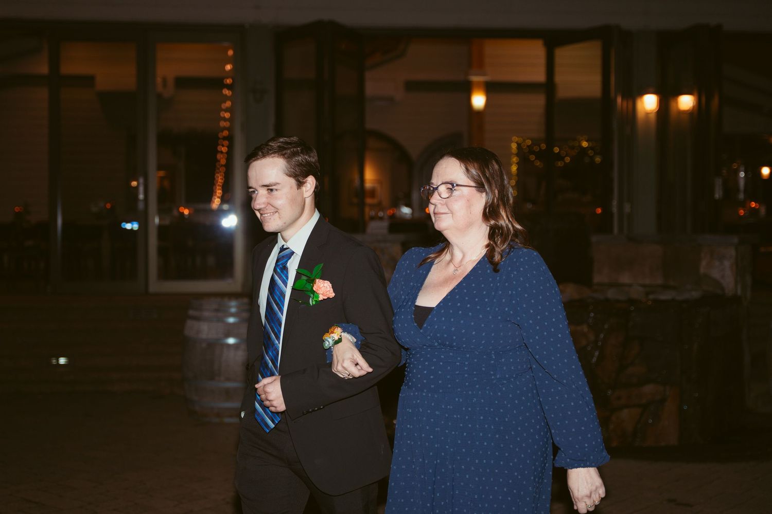 Wedding guests gather under warm outdoor lighting during an evening reception.