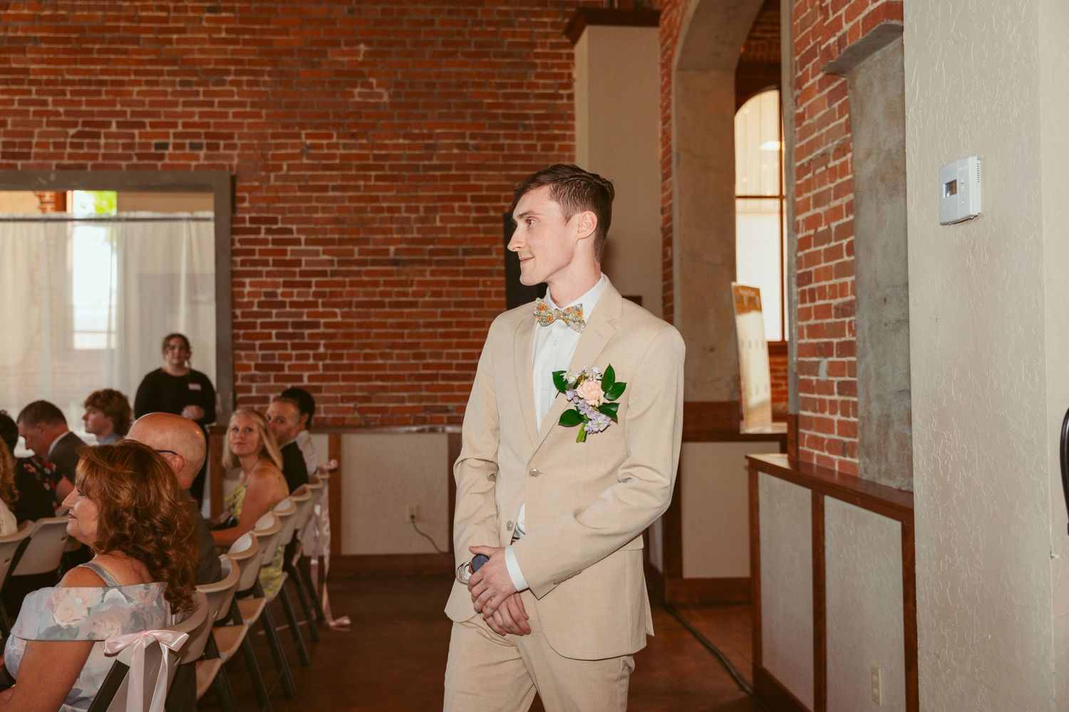 Wedding party gathered in an industrial-style venue with exposed brick walls and hardwood floors.