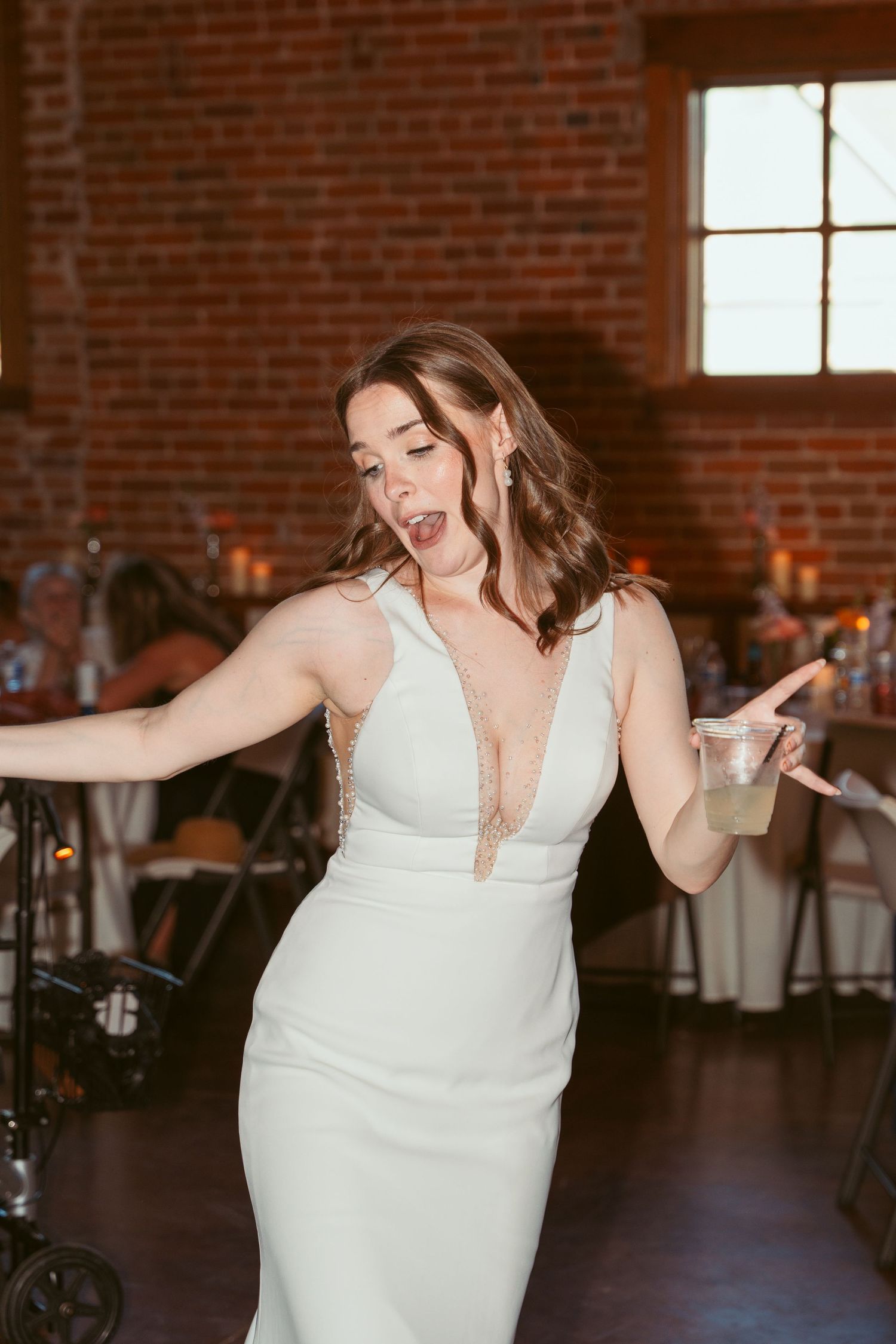 Wedding celebration with joyful dancing in an industrial-style reception space.