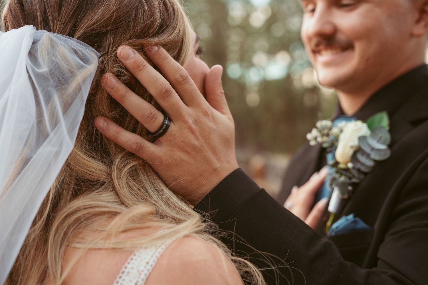 Tender wedding moment captured in close-up with delicate veil details.