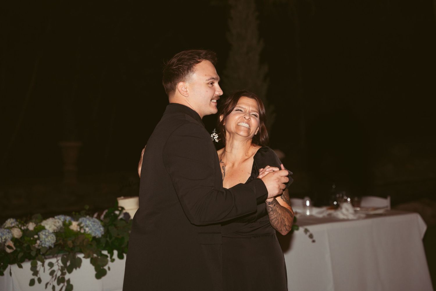 A couple shares a romantic dance under the stars during an outdoor evening wedding reception.