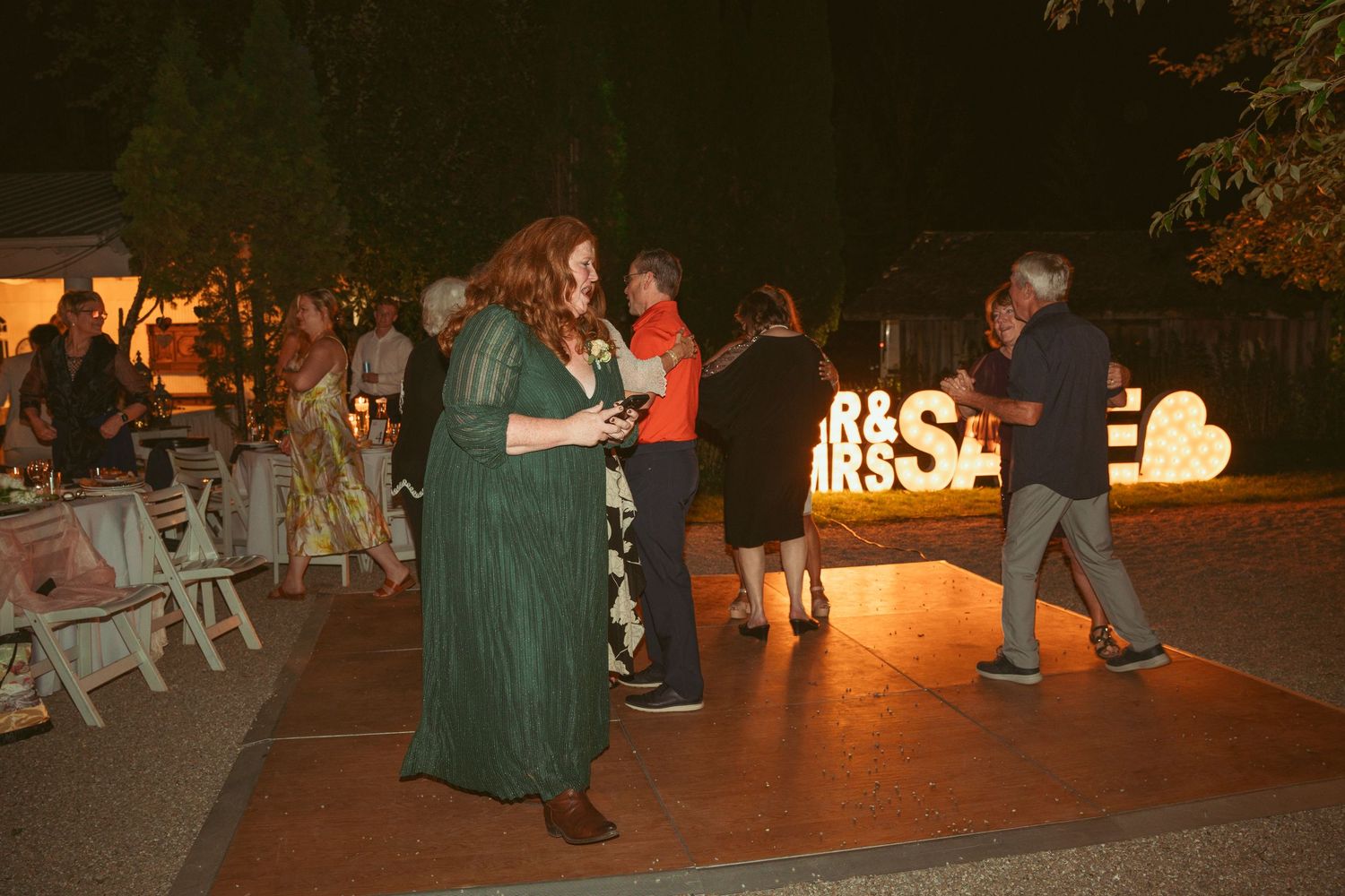 Guests dancing on an outdoor dance floor with illuminated signage in the background.
