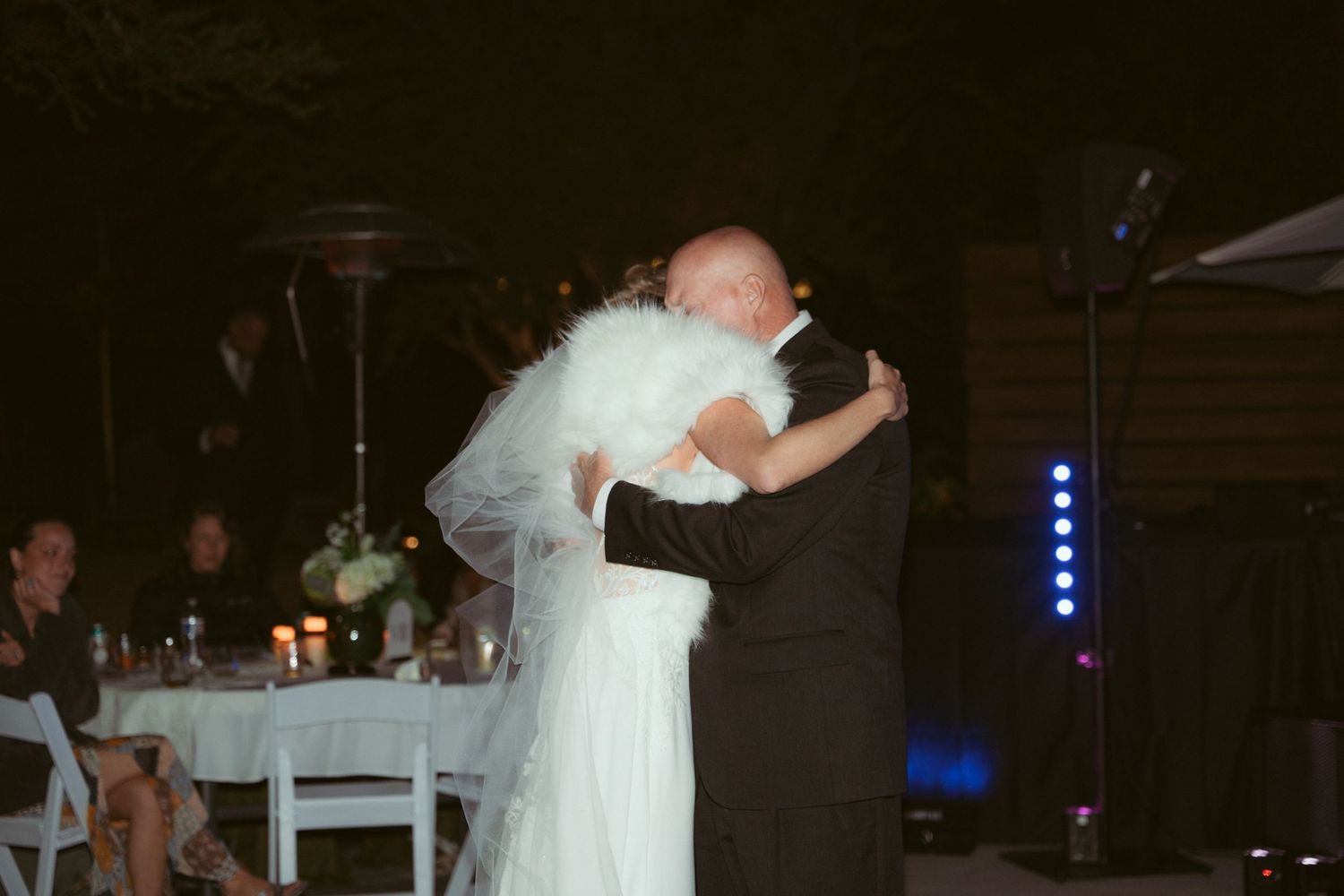 Couple dancing at their evening wedding reception with atmospheric blue lighting.