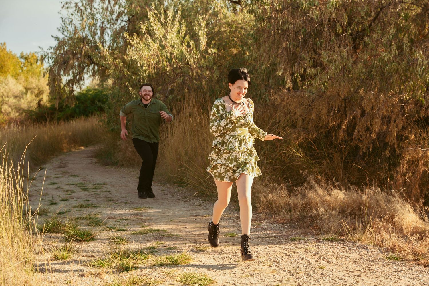 A couple dances and twirls together on a desert trail during golden hour.
