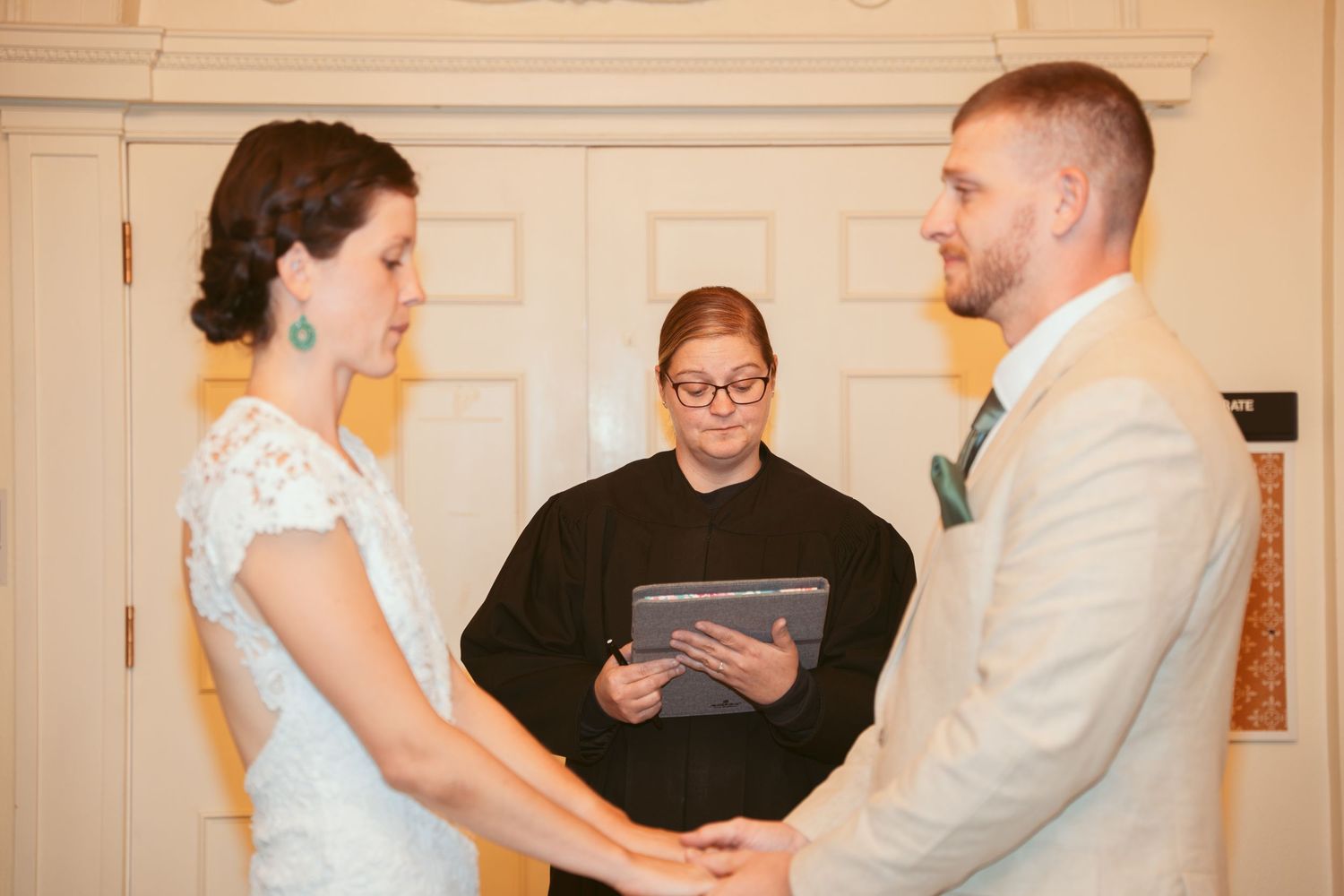 An intimate wedding ceremony unfolds in a classic room with white columns and ornate details.