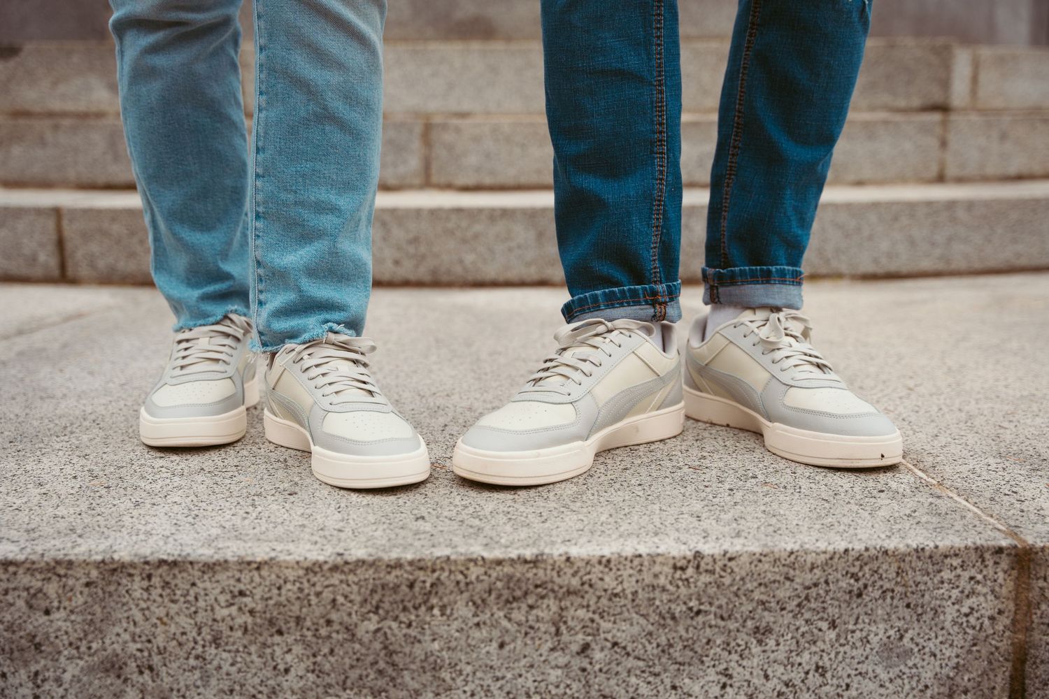 Detail shot of feet in casual shoes standing on concrete steps.