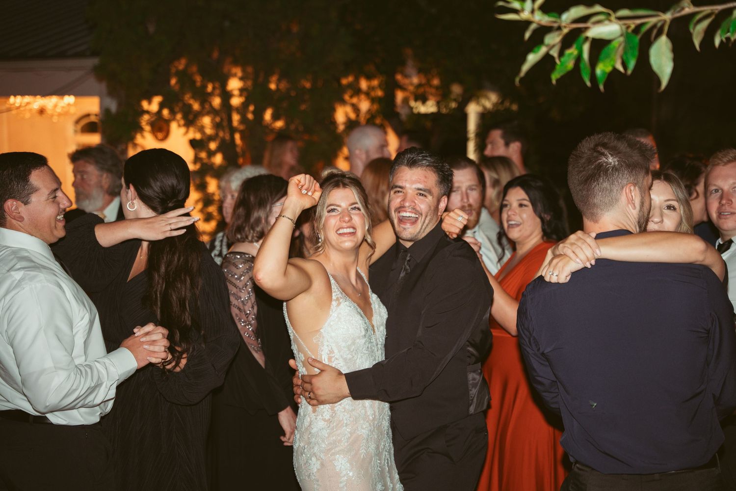 Wedding celebration on a dance floor with guests enjoying the festivities under evening lights.