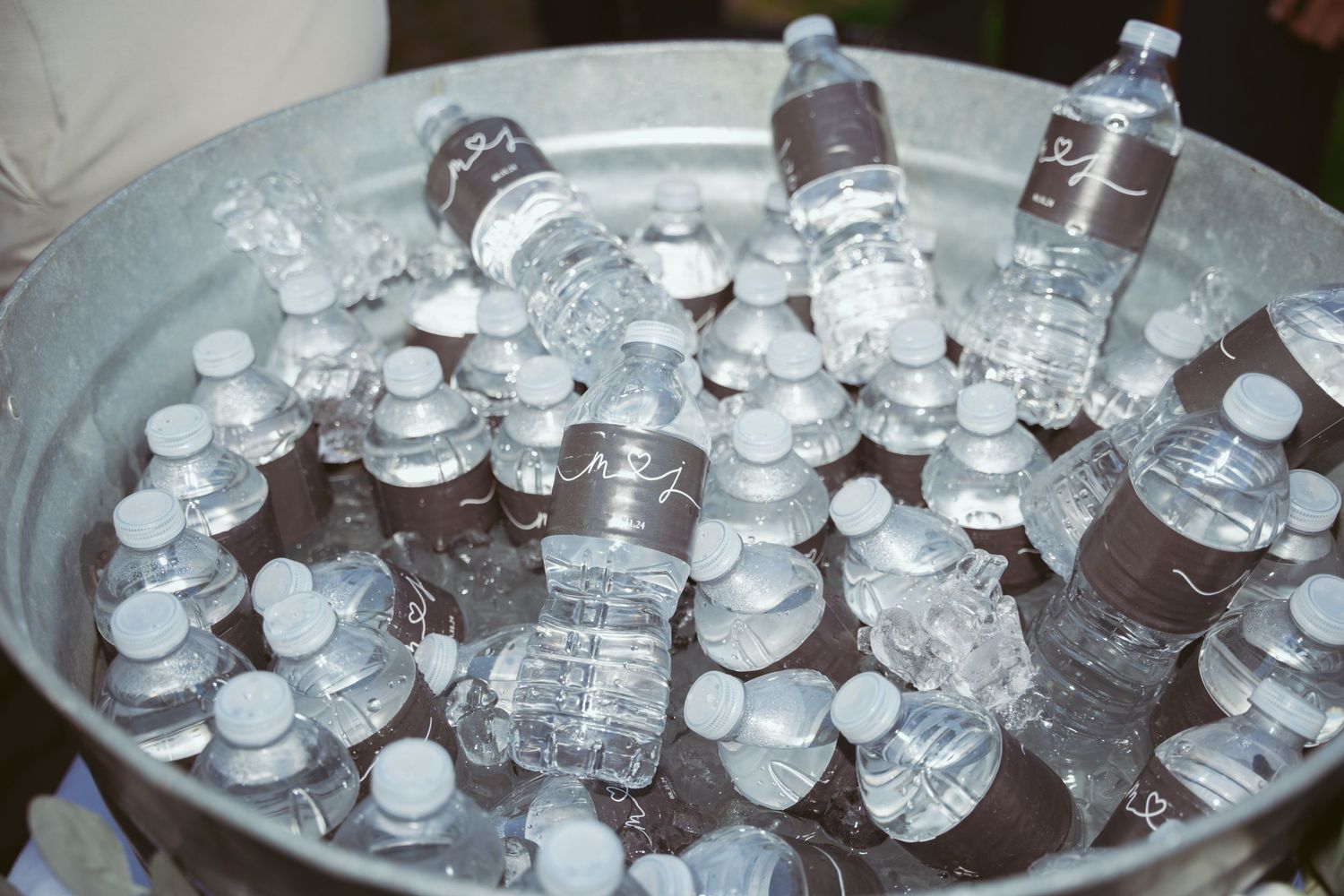 Clear bottles and beverages chilling in ice buckets at an outdoor event.