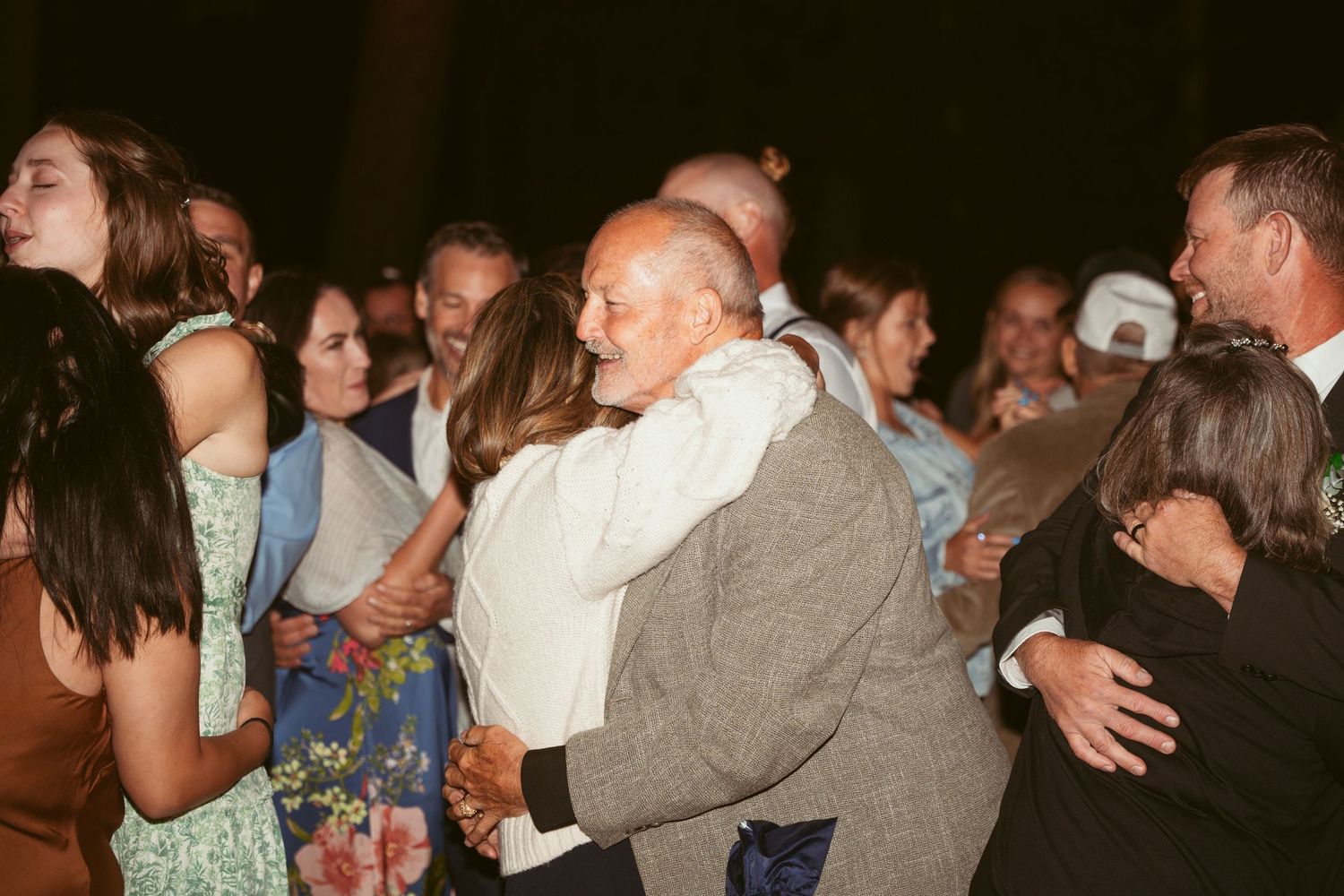 Wedding guests dancing and celebrating on a packed dance floor during evening reception.
