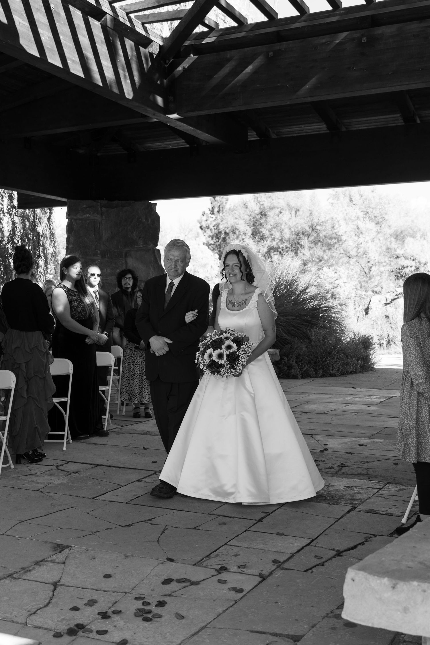 Black and white photo of traditional wedding processional under covered stone patio.
