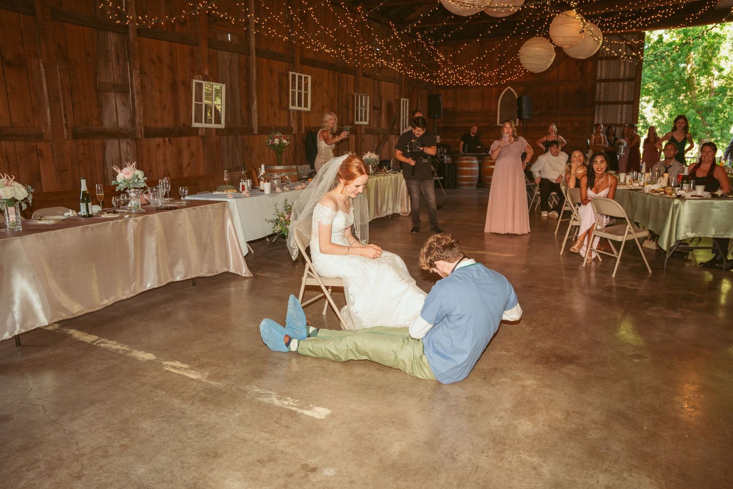 Wedding celebration with entertainment in rustic barn setting with decorative lighting.