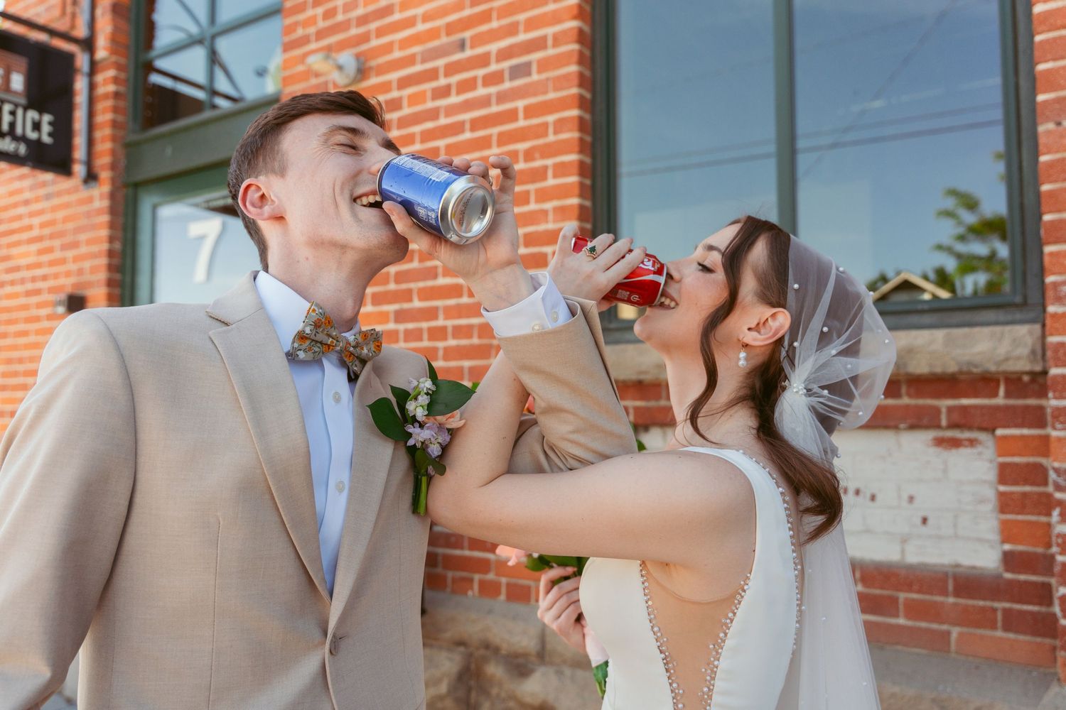 Couple sharing a romantic moment in front of a brick building during a wedding celebration.